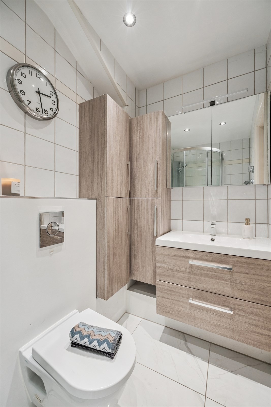 Bad med med nedfelt servant, veggmontert toalett, dusjkabinett og flislagt gulv med elektriske varmekabler. Oppgradert i 2023. Galleribilde