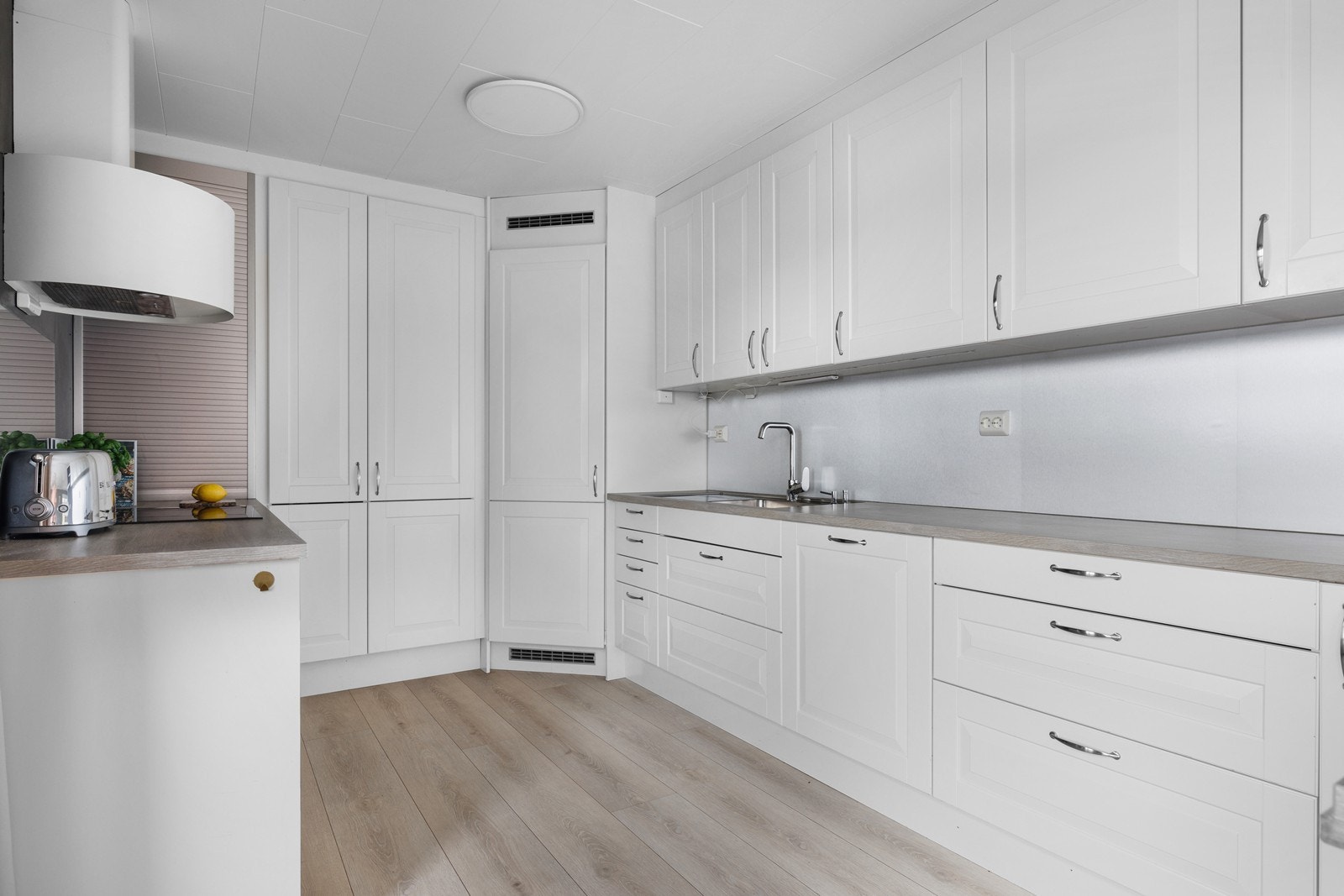 Romslig kjøkkenløsning med godt med skap-og benkplass og integrerte hvitevarer. Galleribilde