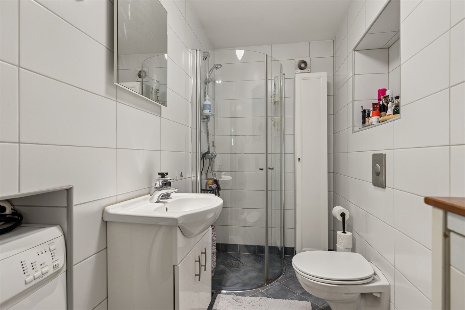 Funksjonelt, flislagt bad i kjelleren med dusj og opplegg for vaskemaskin. Galleribilde