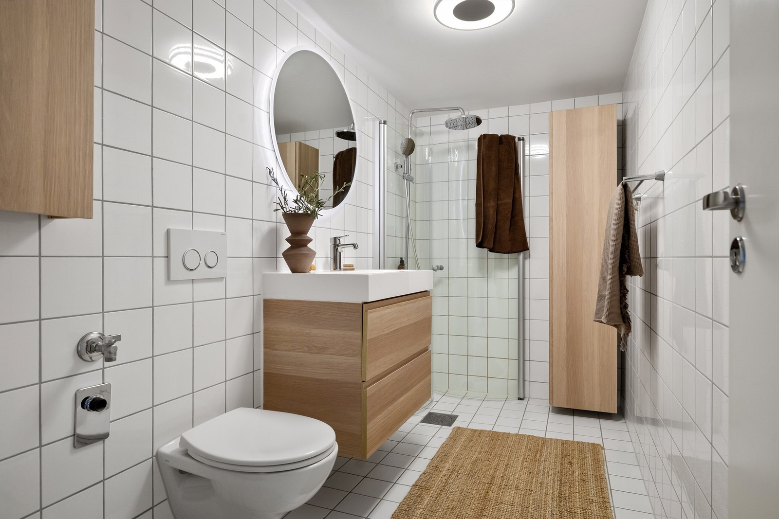 Innbydende og meget romslig bad med lyse fliser, varmekabler i gulv og opplegg for vaskemaskin Galleribilde