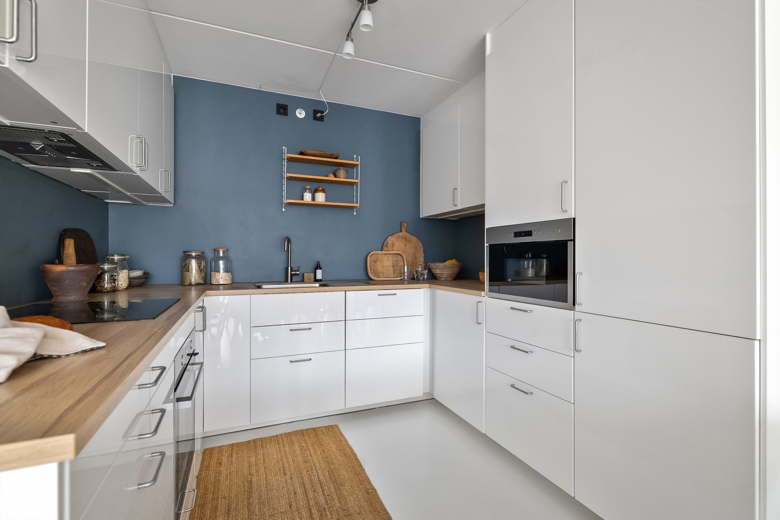 Integrerte hvitevarer som stekeovn, keramisk platetopp med ventilator over, mikrobølgeovn, oppvaskmaskin og kjøleskap med frysedel Galleribilde