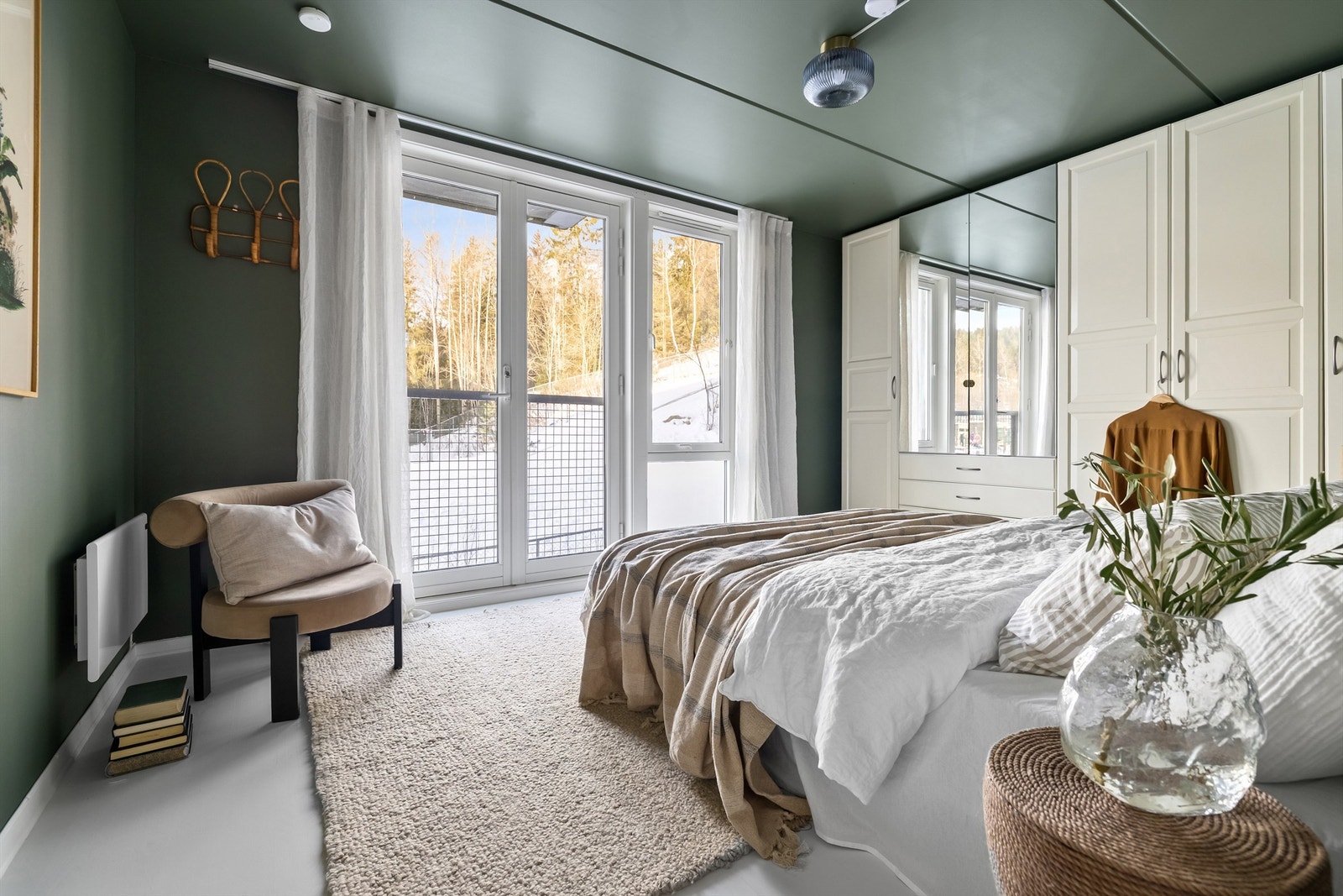 Hovedsoverommet vender ut mot marka med stort vindu og dobbel balkongdør til en fransk balkong Galleribilde