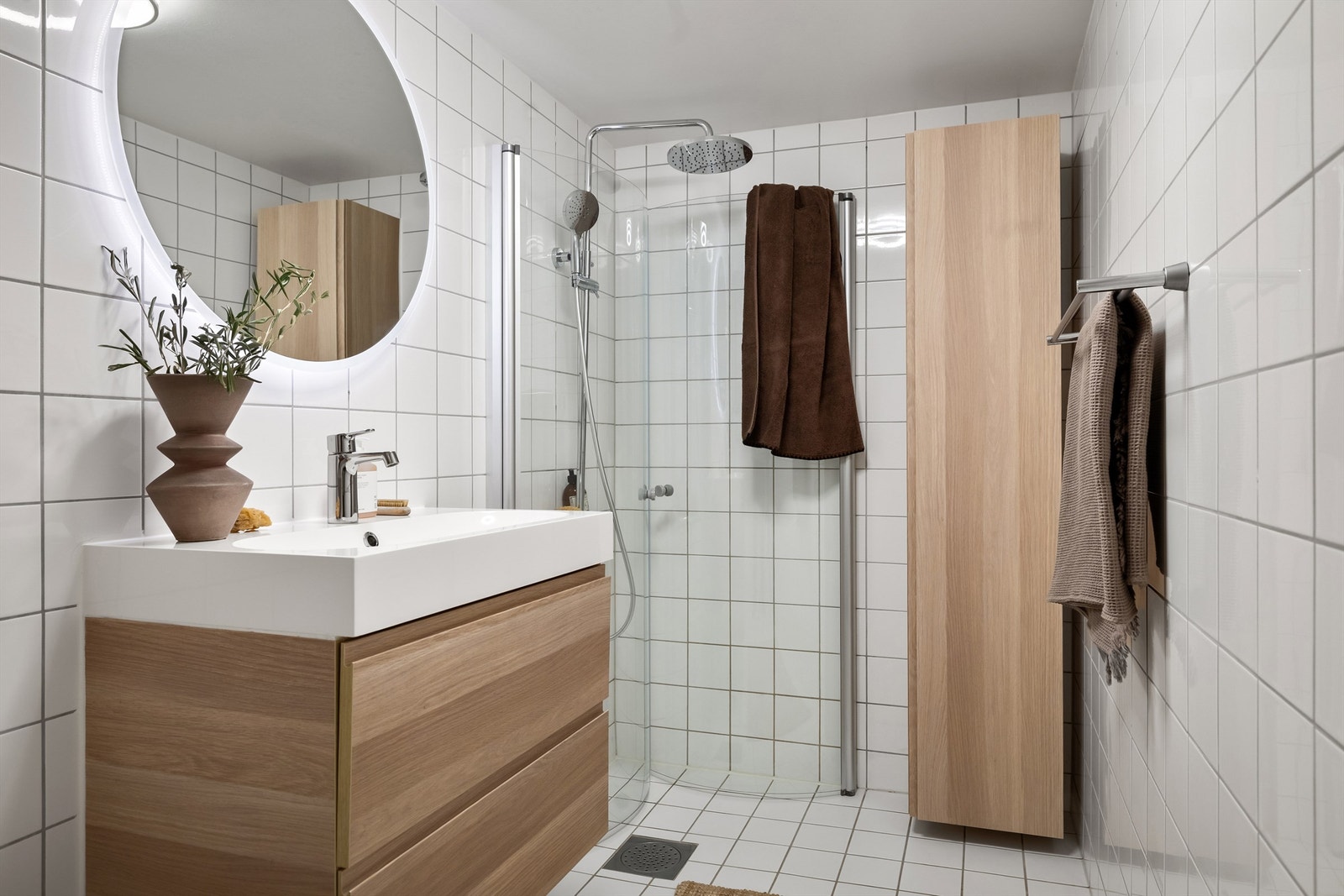 Badet er utstyrt med vegghengt toalett og dusjhjørne med innfellbare glassdører, og dusjsett med rainshower Galleribilde