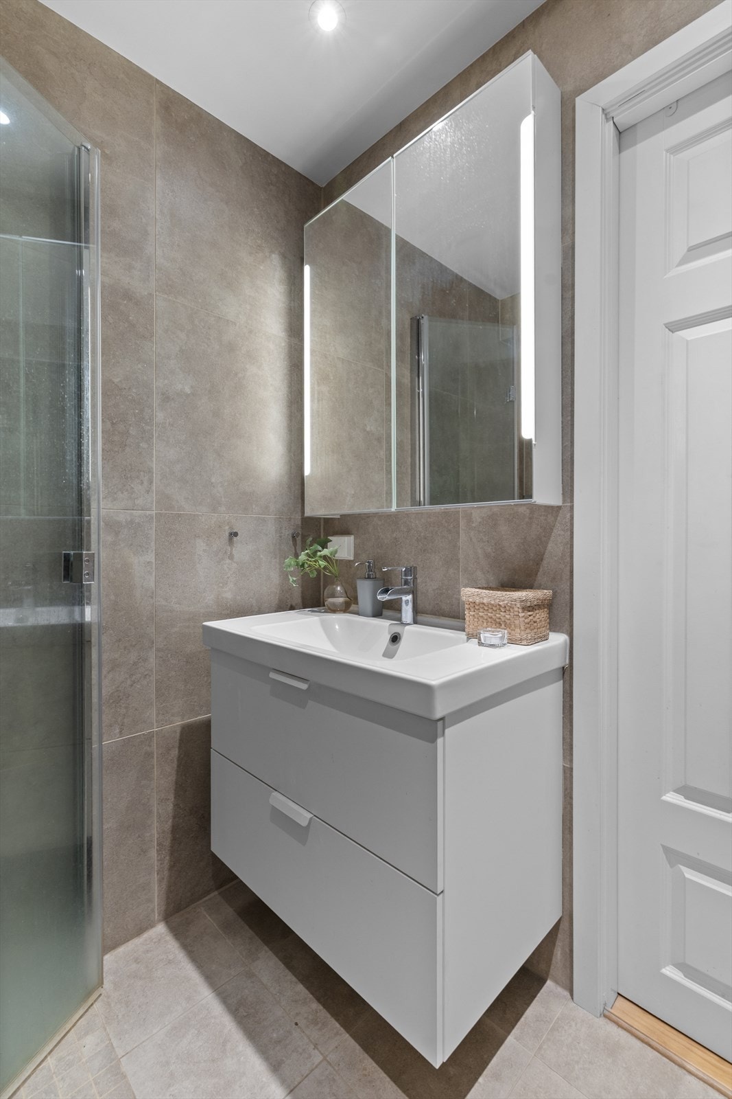 Badet har en pen servant med tilhørende speilskap som gir rikelig med oppbevaring og god belysning. Galleribilde