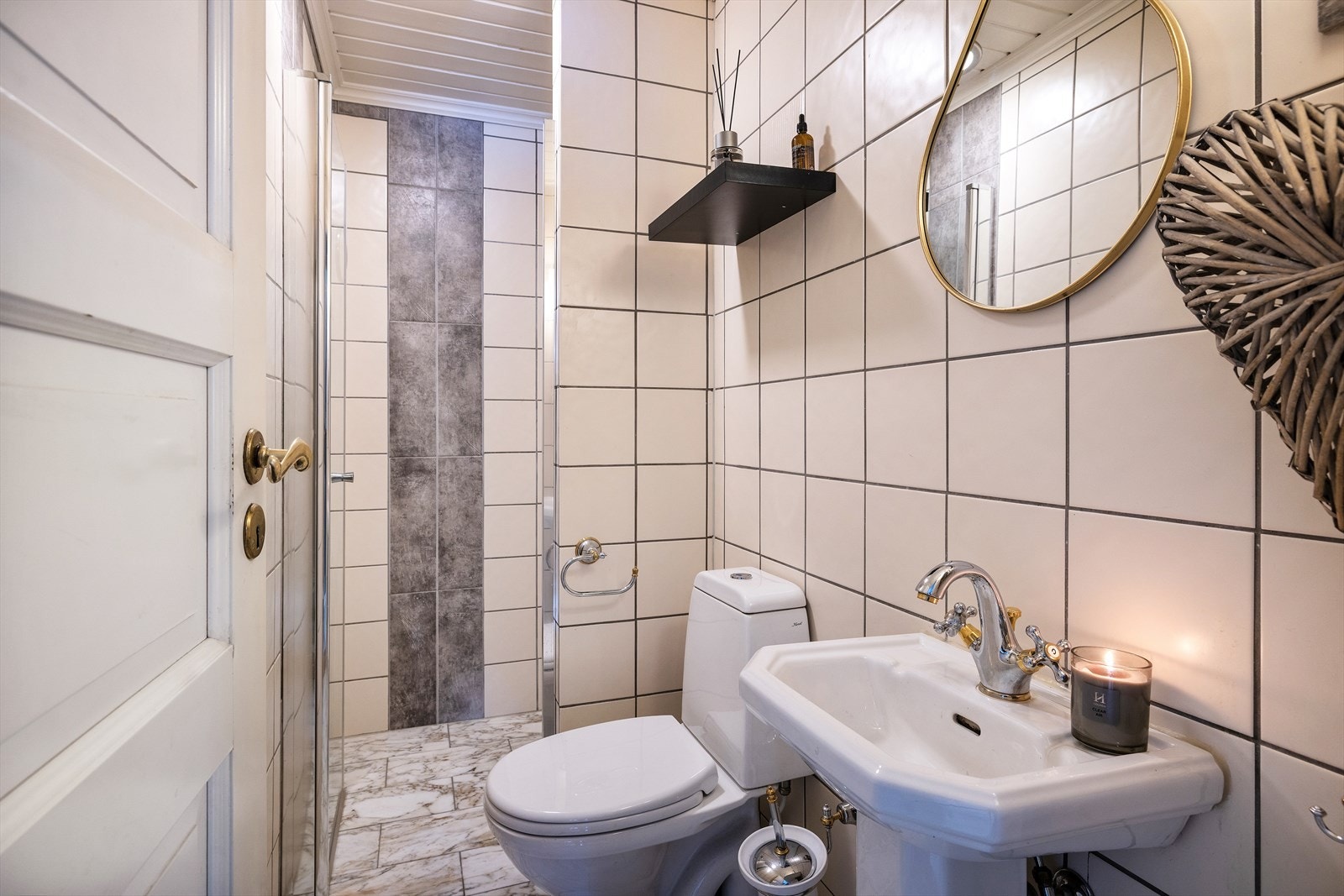 Badet i 1.etasje er flislagt med varme i gulv. Servantinnredning med servant, speil, toalett og dusj nisje. Galleribilde