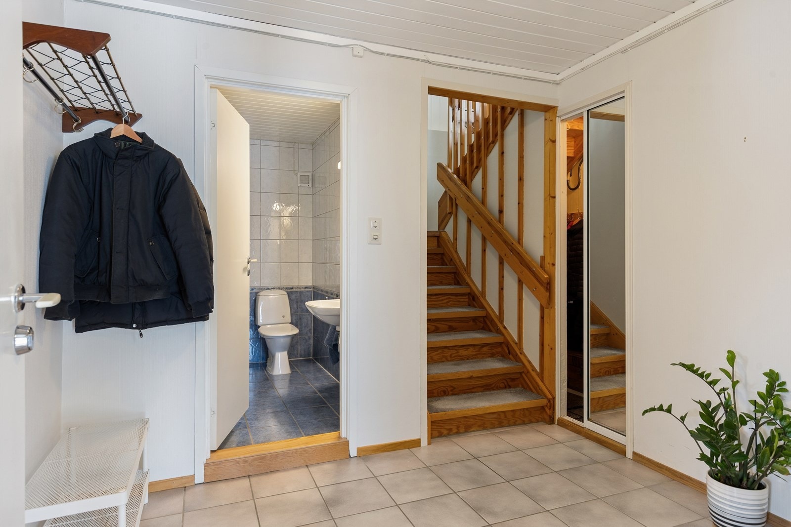 Hallen i underetasjen med flislagt gulv, trapp opp til første etasje og tilgang til bad. Galleribilde