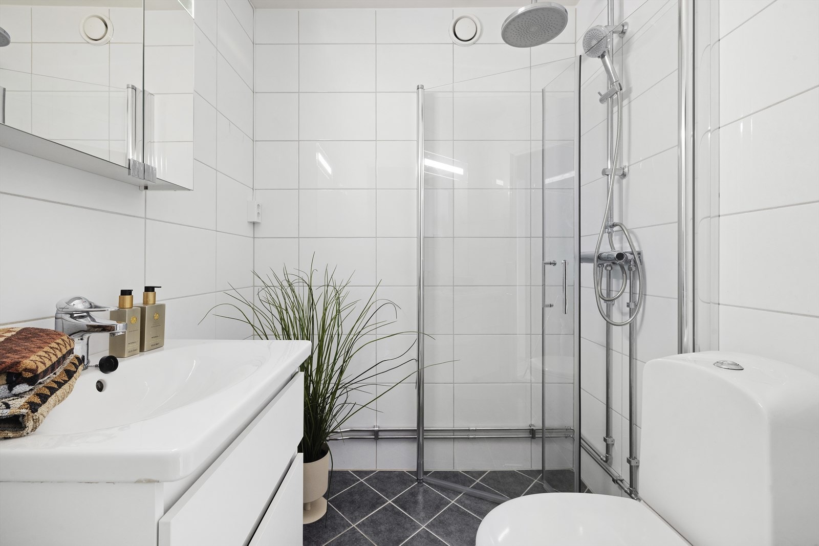 Pent baderom med nøytrale flislagte vegger og gulv, med varmekabler Galleribilde