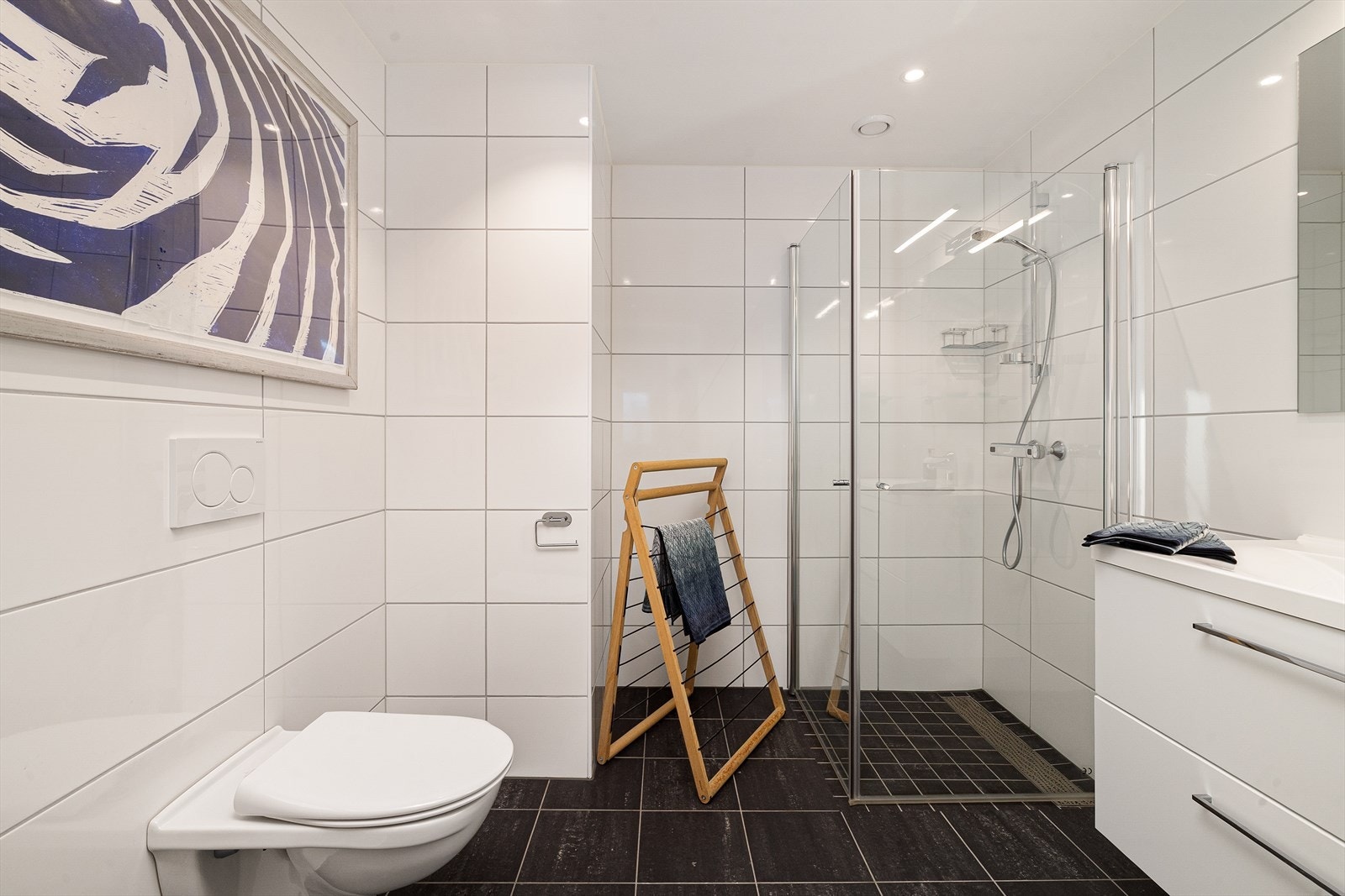 Rommet er utstyrt med servant over skuffinnredning samt dusjhjørne med innfellbare glassvegger og vegghengt toalett Galleribilde