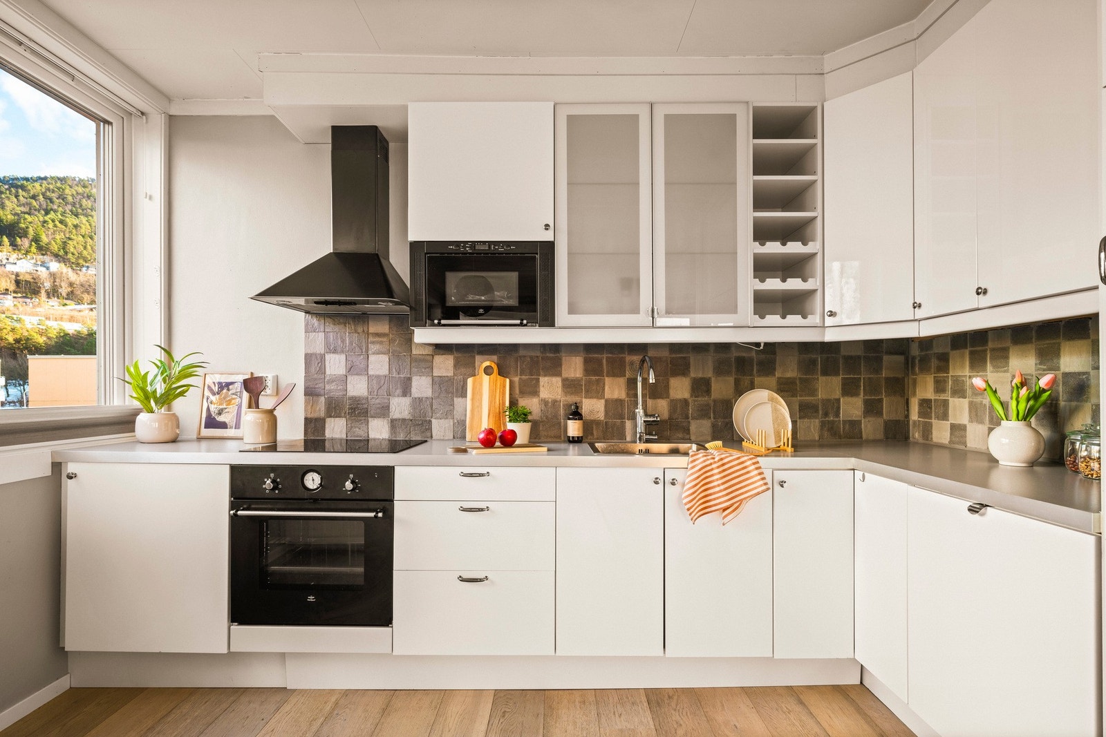 Kjøkkeninnredningen består av slette fronter, ett av overskapene har glassfront, laminat benkeplate, over benkeplaten er det benyttet fliser, stål oppvaskkum og ventilator. Galleribilde