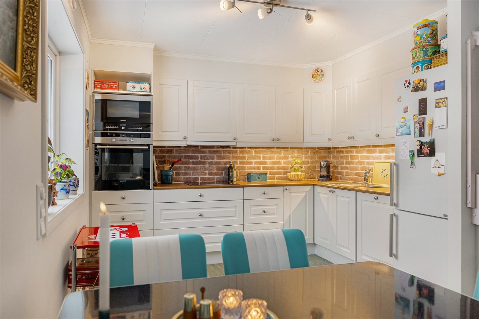 Kjøkkenet har en praktisk utforming med mye skap- og benkeplass og detaljer som murstein i sprutsonen. Galleribilde