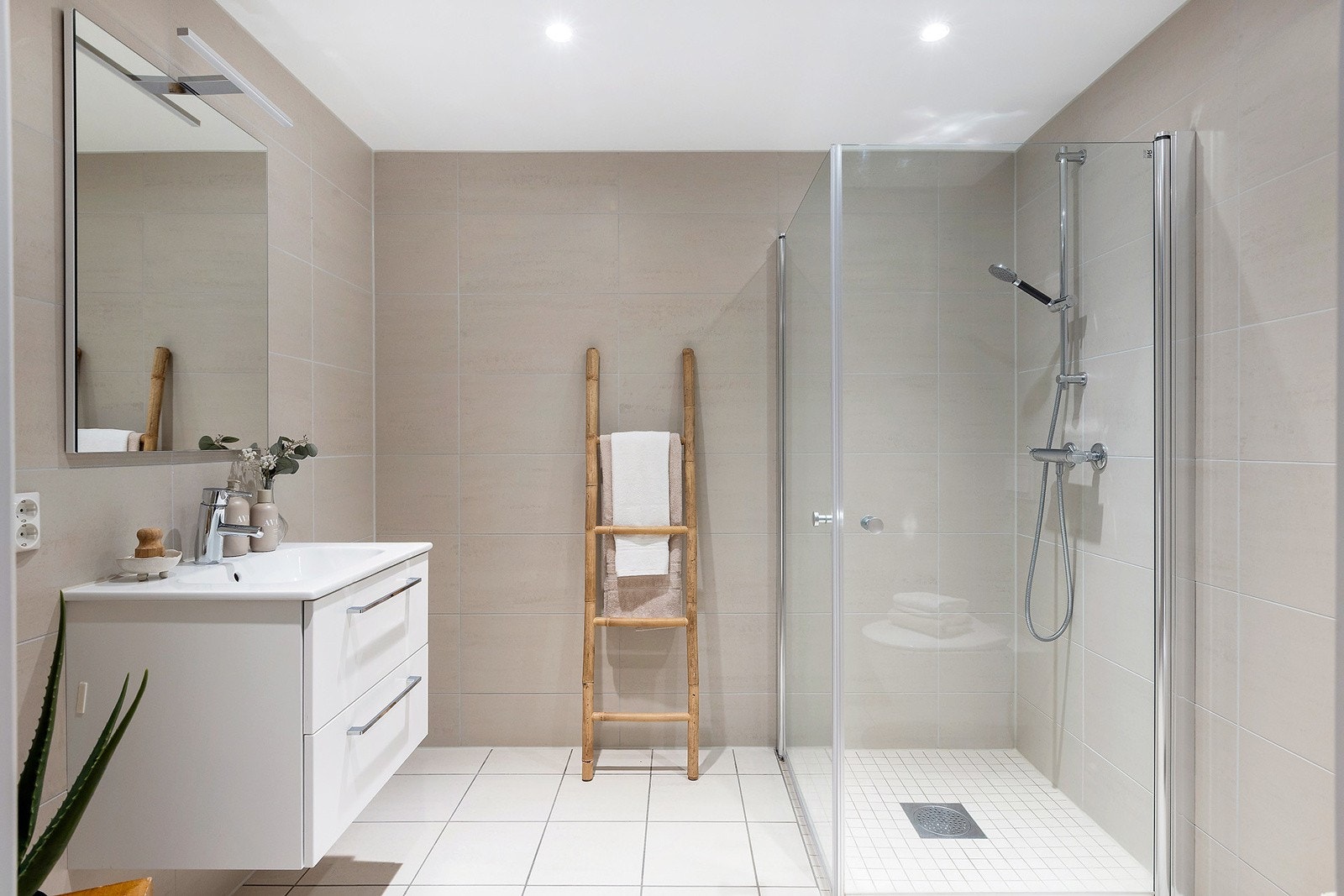 Delikat flislagt bad med downlights i himling, vegghengt toalett og inn-utstående dusjvegger. Galleribilde