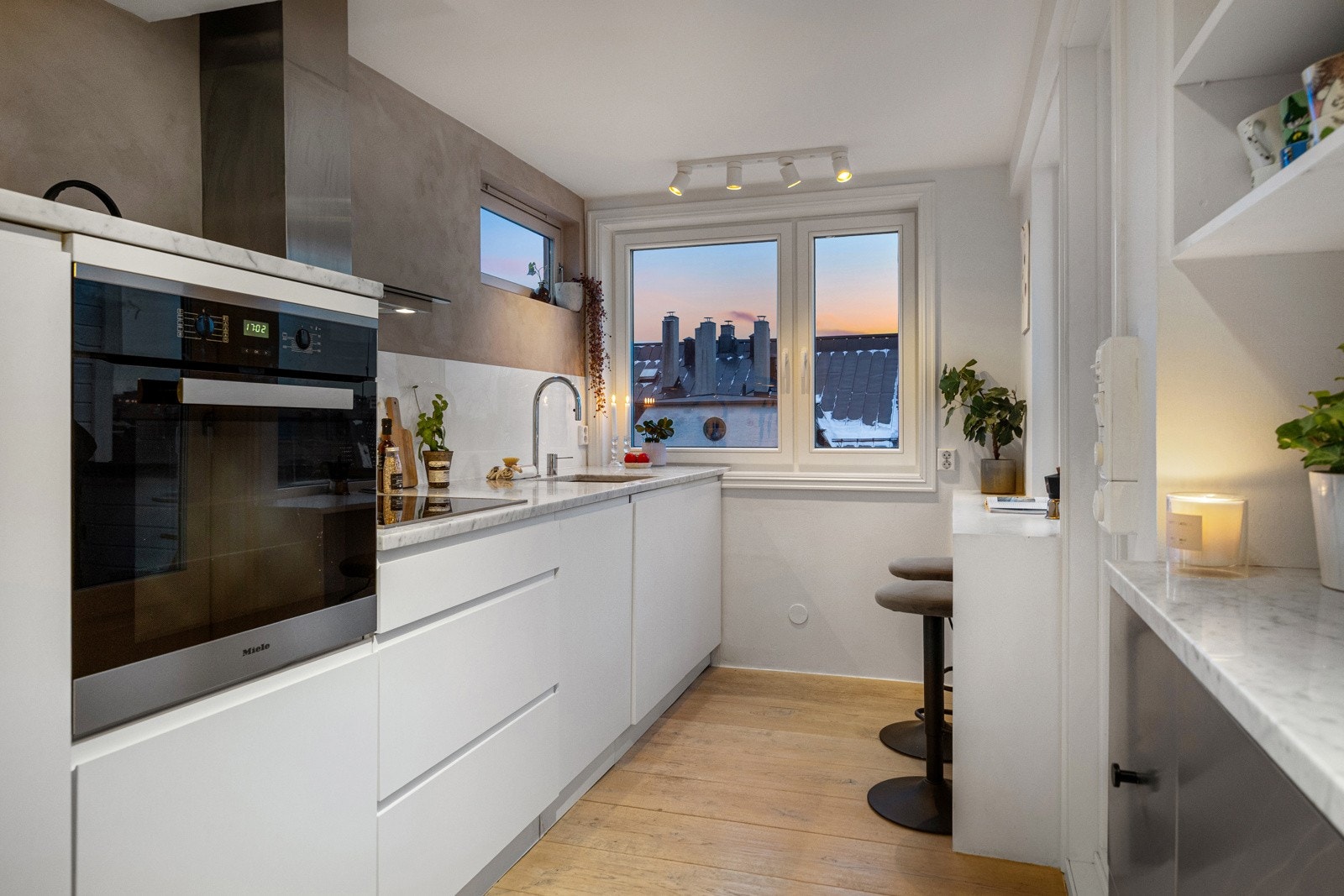 Kjøkkenet er stilrent innredet med slette fronter og benkeplate av stein som gir et helhetlig og moderne uttrykk. Innredningen har ekstra dybde på 80 cm, mot standard 60 cm, noe som gir betydelig mer arbeidsplass på benk og økt oppbevaringskapasitet. Galleribilde