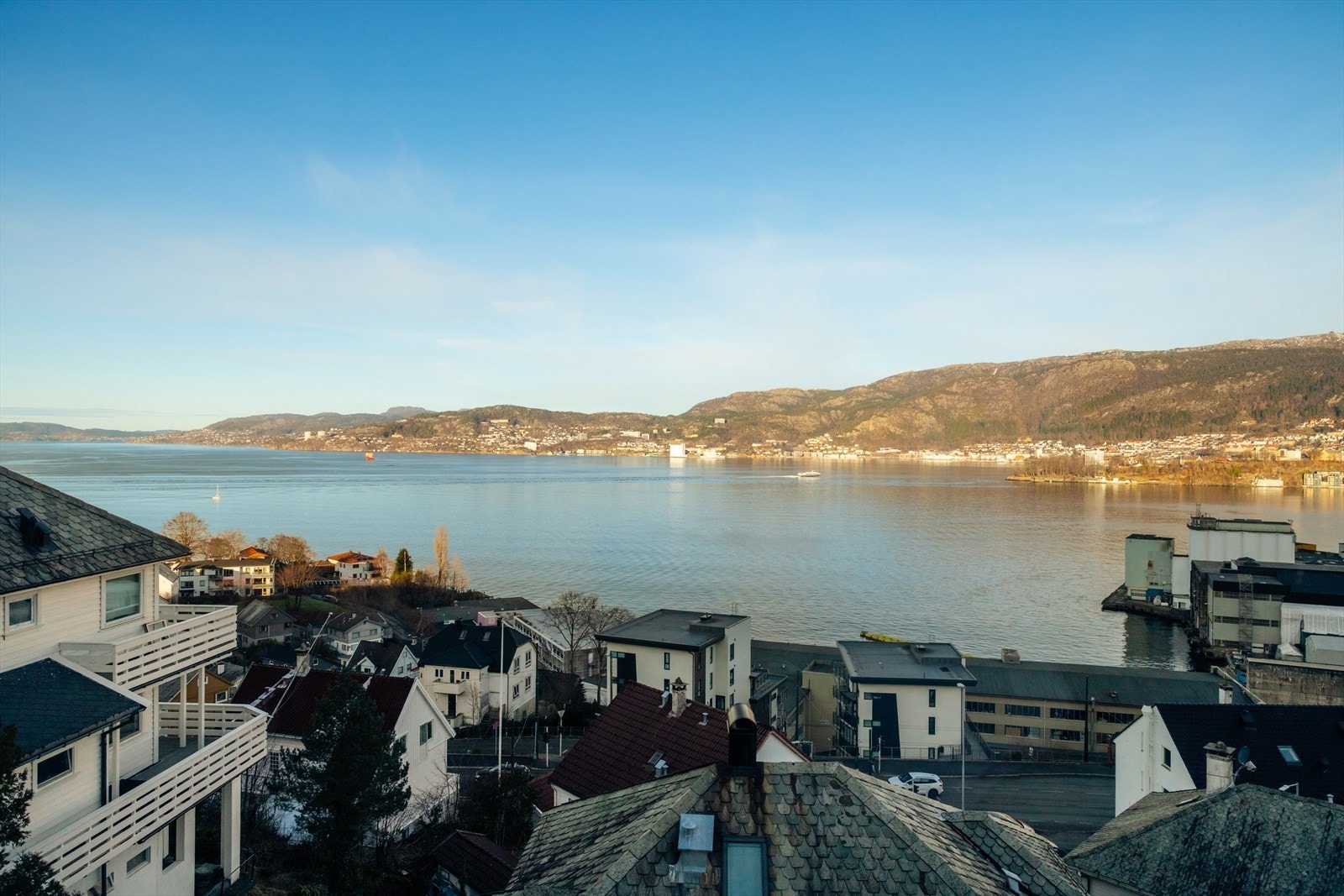 Fri og åpen utsikt mot sjøen og omkringliggende landskap, med god avstand til bebyggelsen foran som gir en luftig og rolig steming Galleribilde