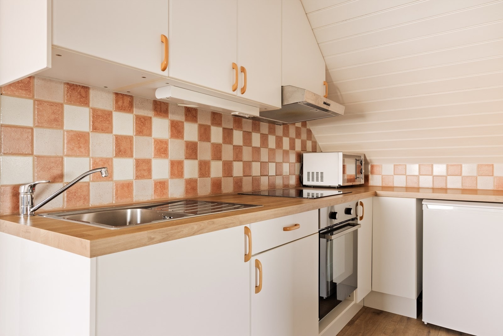 Kjøkkenet er utstyrt med skapinnredning, benkeplate i heltre og nødvendige hvitevarer Galleribilde