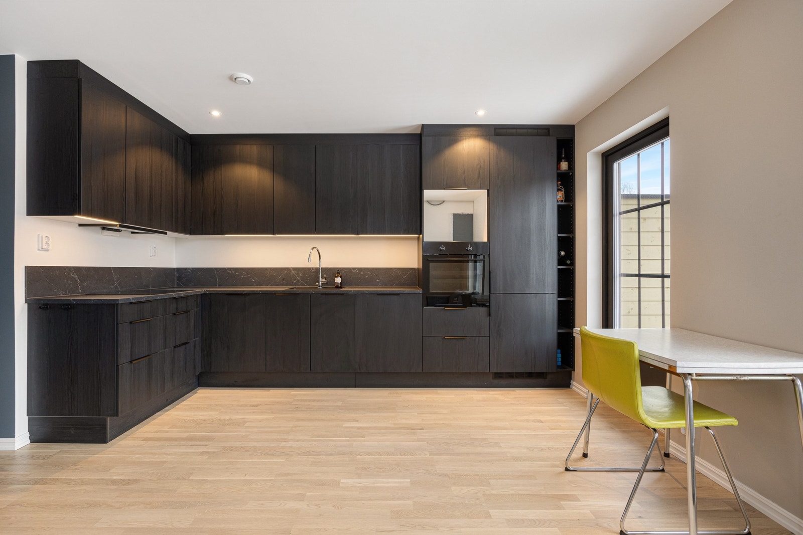 Stilrent og moderne kjøkken i L-form med sorte, glatte fronter og god skapplass. Galleribilde