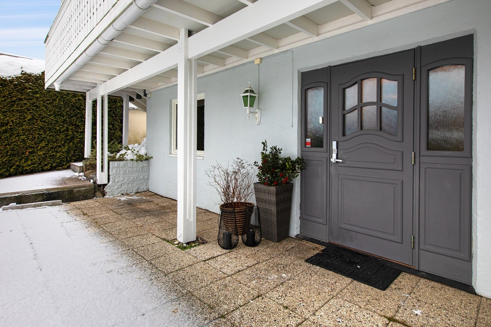 Overbygget inngangsparti i underetasjen med malt hovedytterdør fra 2007. Galleribilde