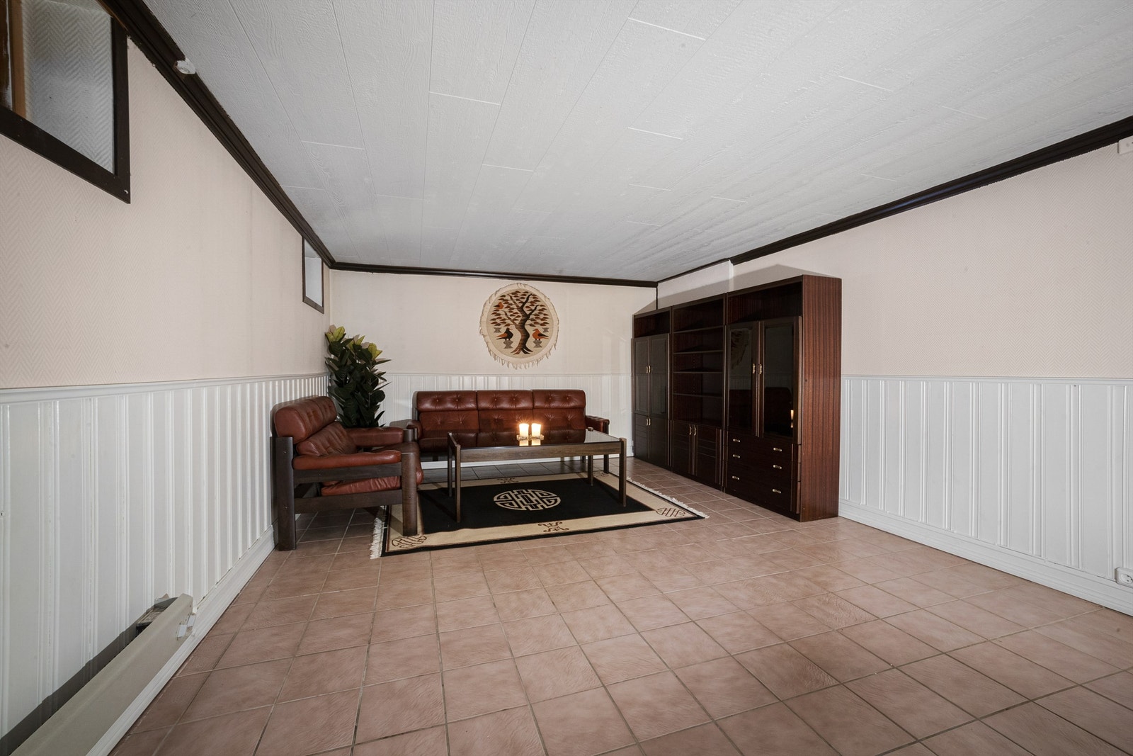 Rom benyttet som kjellerstue er innredet med sofa, bord og veggseksjon Galleribilde