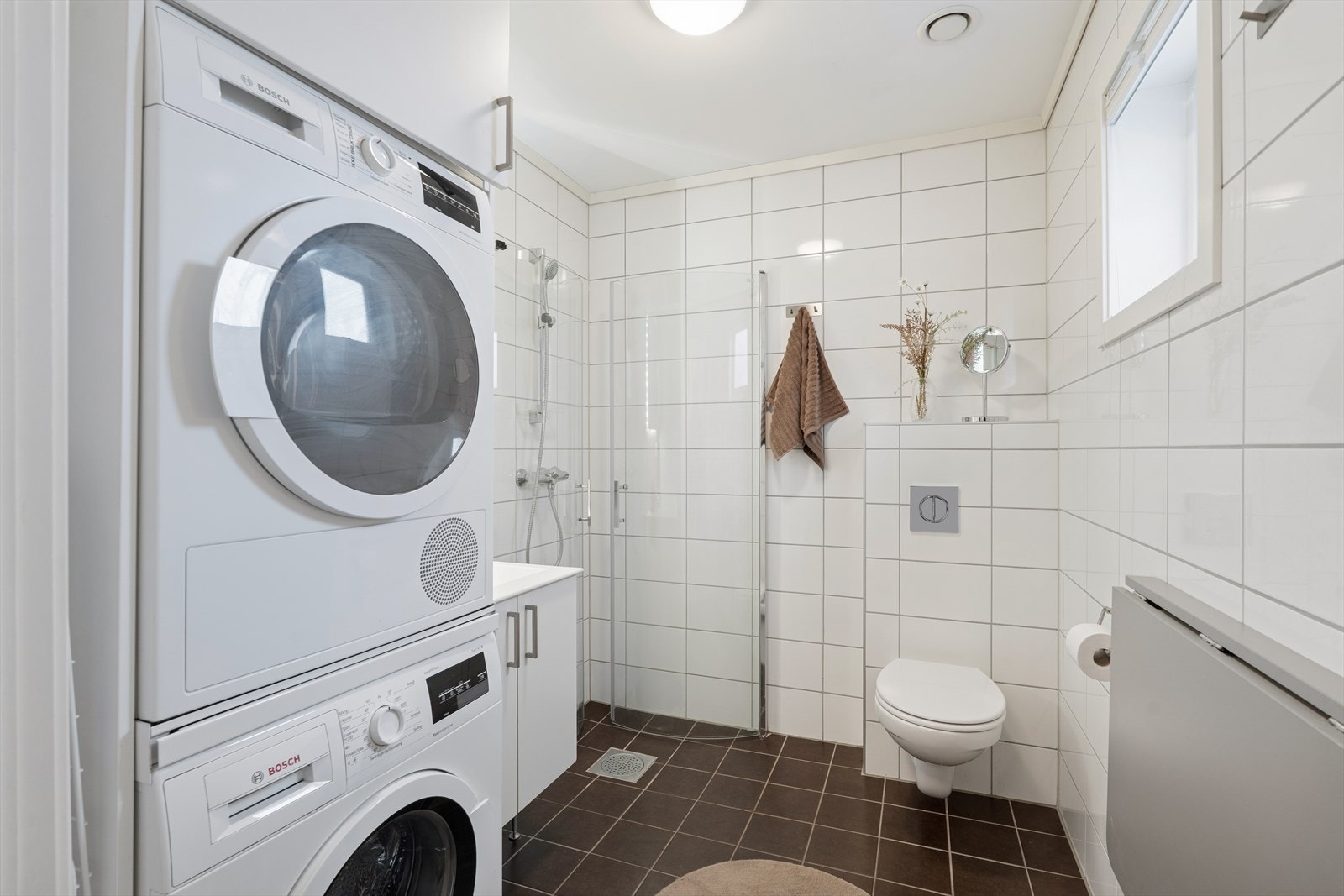 Badet er innredet med servantinnredning, skap, dusjdører, wc og opplegg for vaskemaskin. Galleribilde