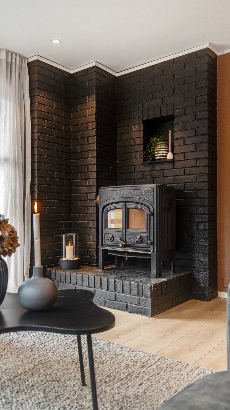 Teglsteinsveggen malt i sort gjør at ovnen glir sømløst inn i rommet. Galleribilde