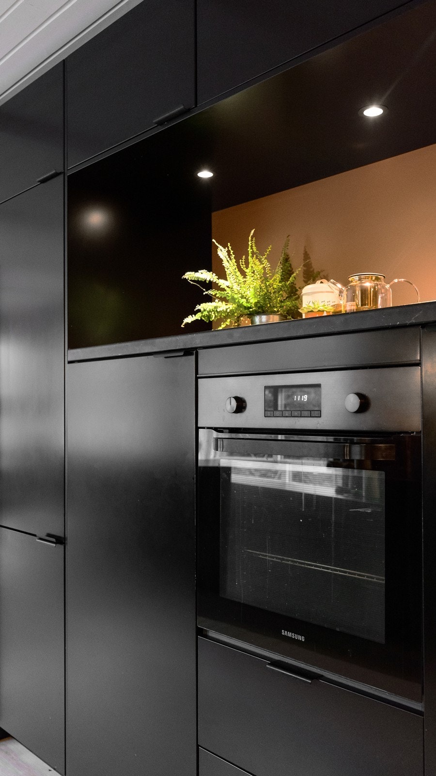 Detaljer som nisjehyller med spotter og integrert stekeovn i arbeidshøyde løfter både estetikken og brukervennligheten. Galleribilde