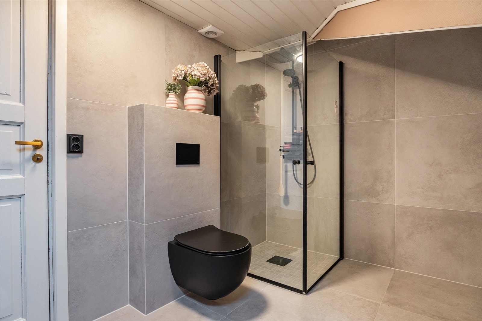 Stilig vegghengt toalett i sort og flott dusjhjørne med mosaikkfliser på gulv. Galleribilde