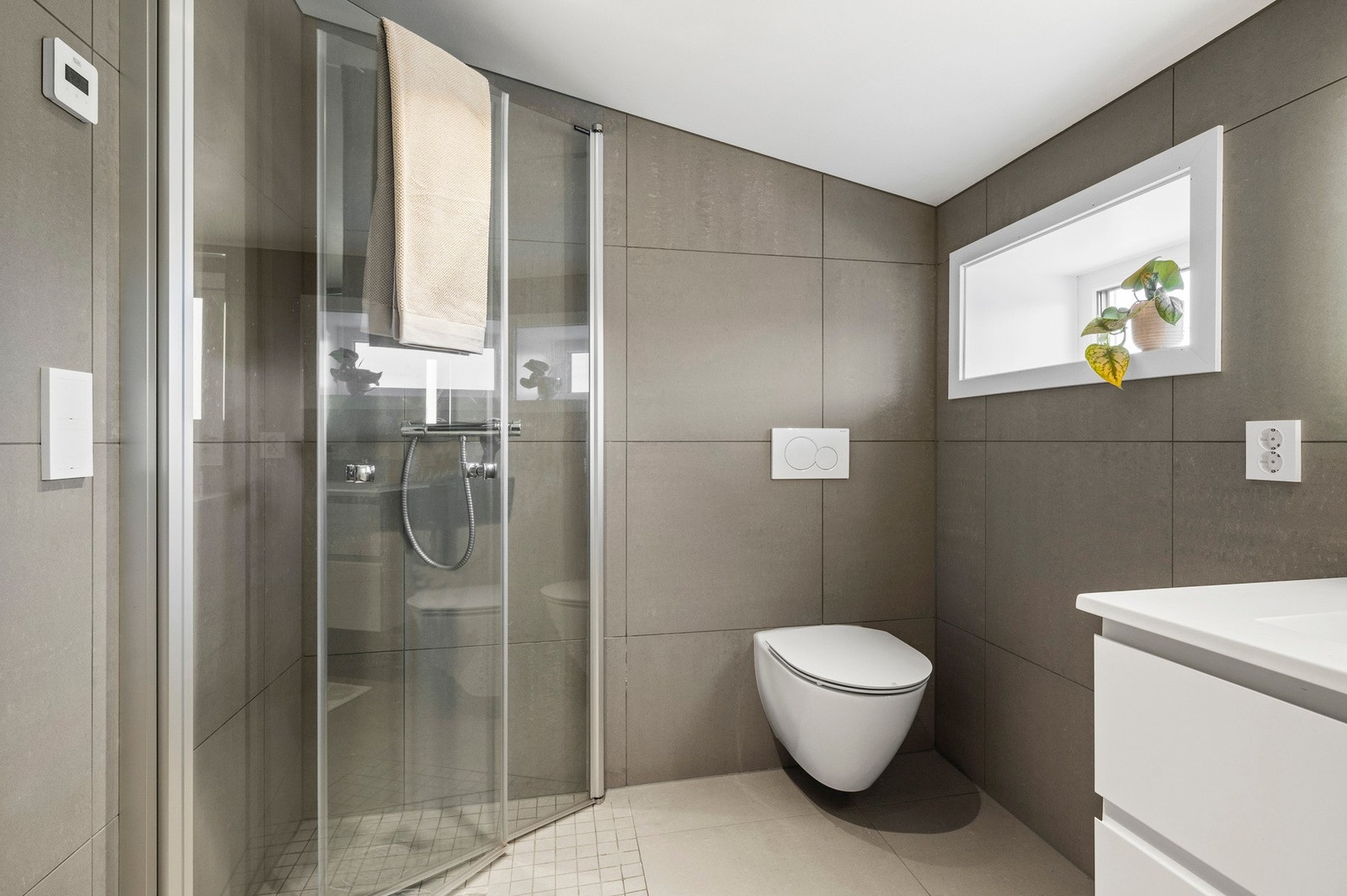 Badet er innredet med baderomsinnredning med støpt marmorsservant, speil med integrert LED-belysning, veggmontert toalett og dusjhjørne. Galleribilde