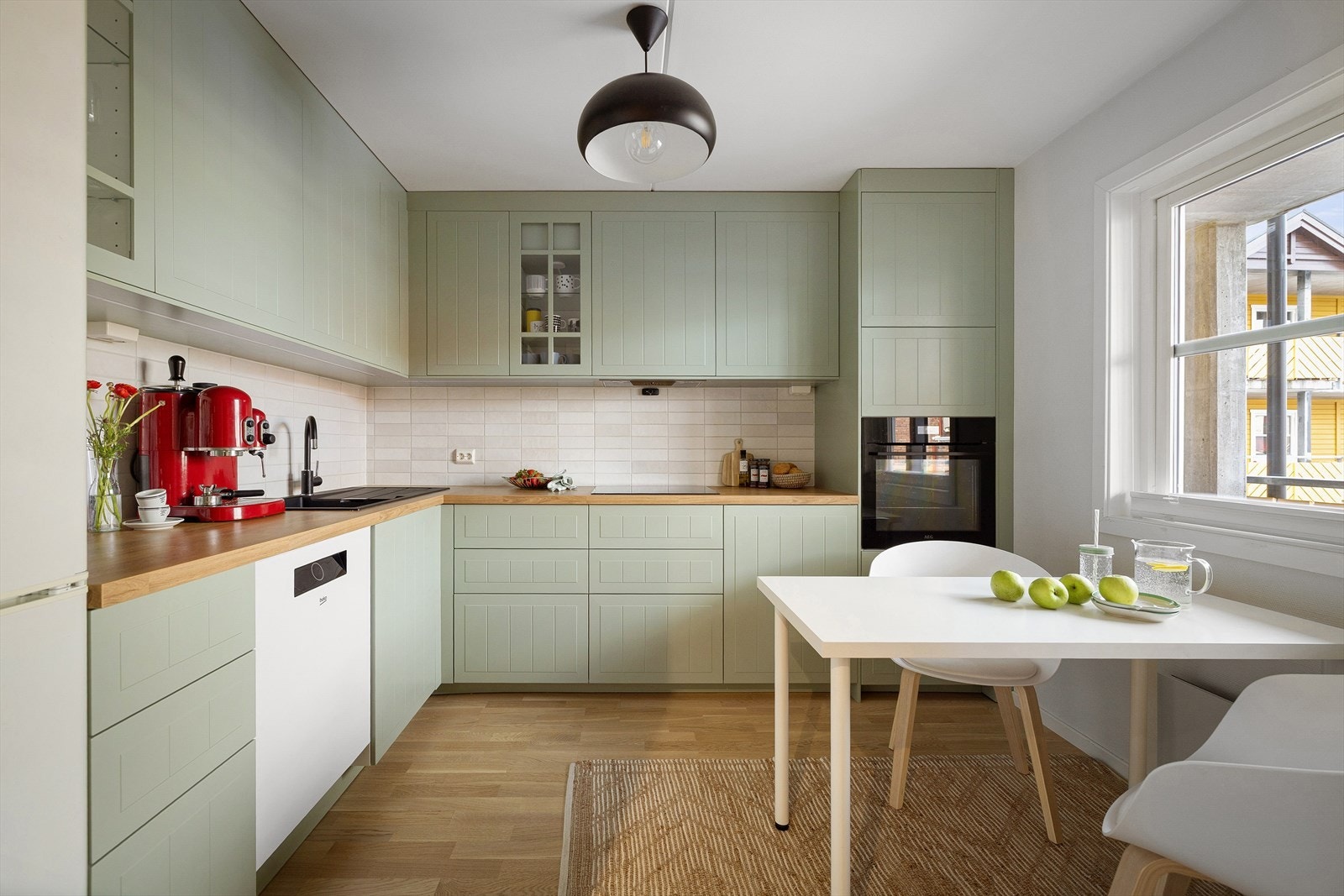 Svalgrønne fronter (IKEA) med hvite fliser på bakveggen og en pen benkeplate som matcher gulvet. Alt er svært harmonisk og tiltalende, og ved vinduet finner du en perfekt plass til frokostbordet som fanger inn soloppgangen. Galleribilde