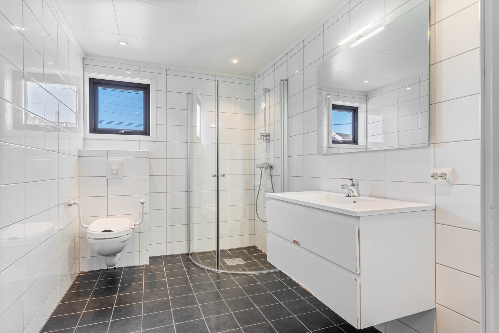 Flott fliselagt bad med varmekabler, vegghengt toalett, downlights og dusjhjørne Galleribilde