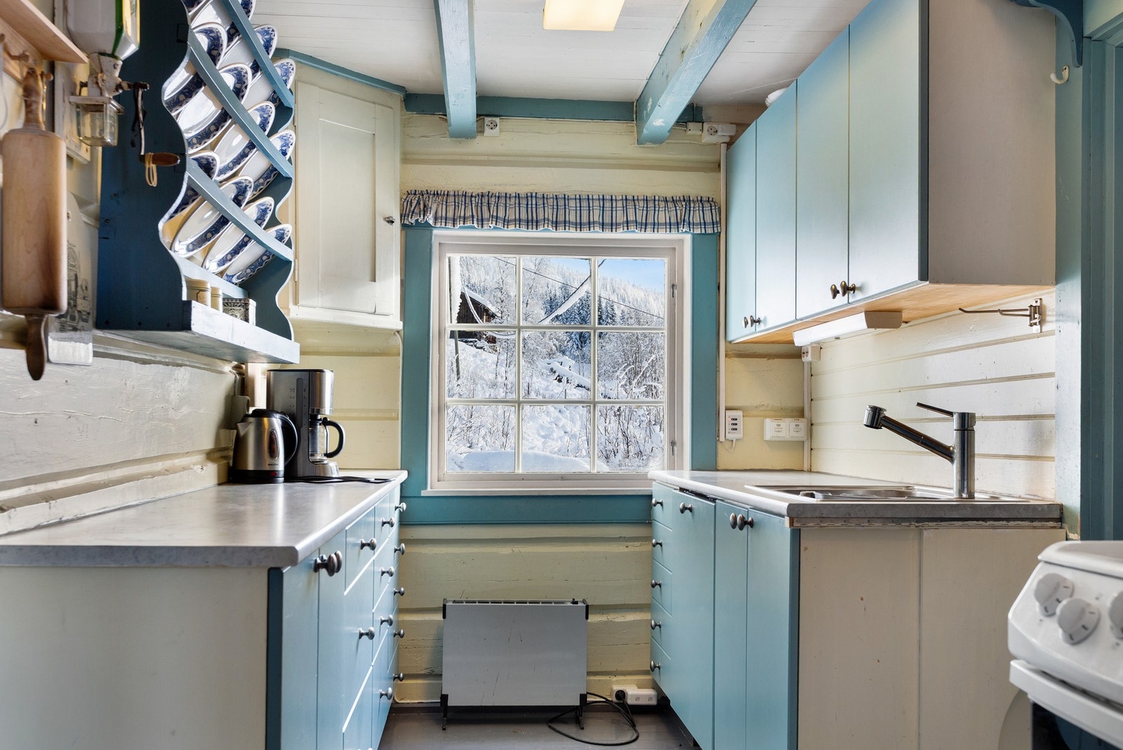 Kjøkkeninnredning med heltreskrog og skufferekke, over- og underskap med malte slette fronter. Det er integrert oppvaskmaskin, samt frittstående komfyr. Galleribilde