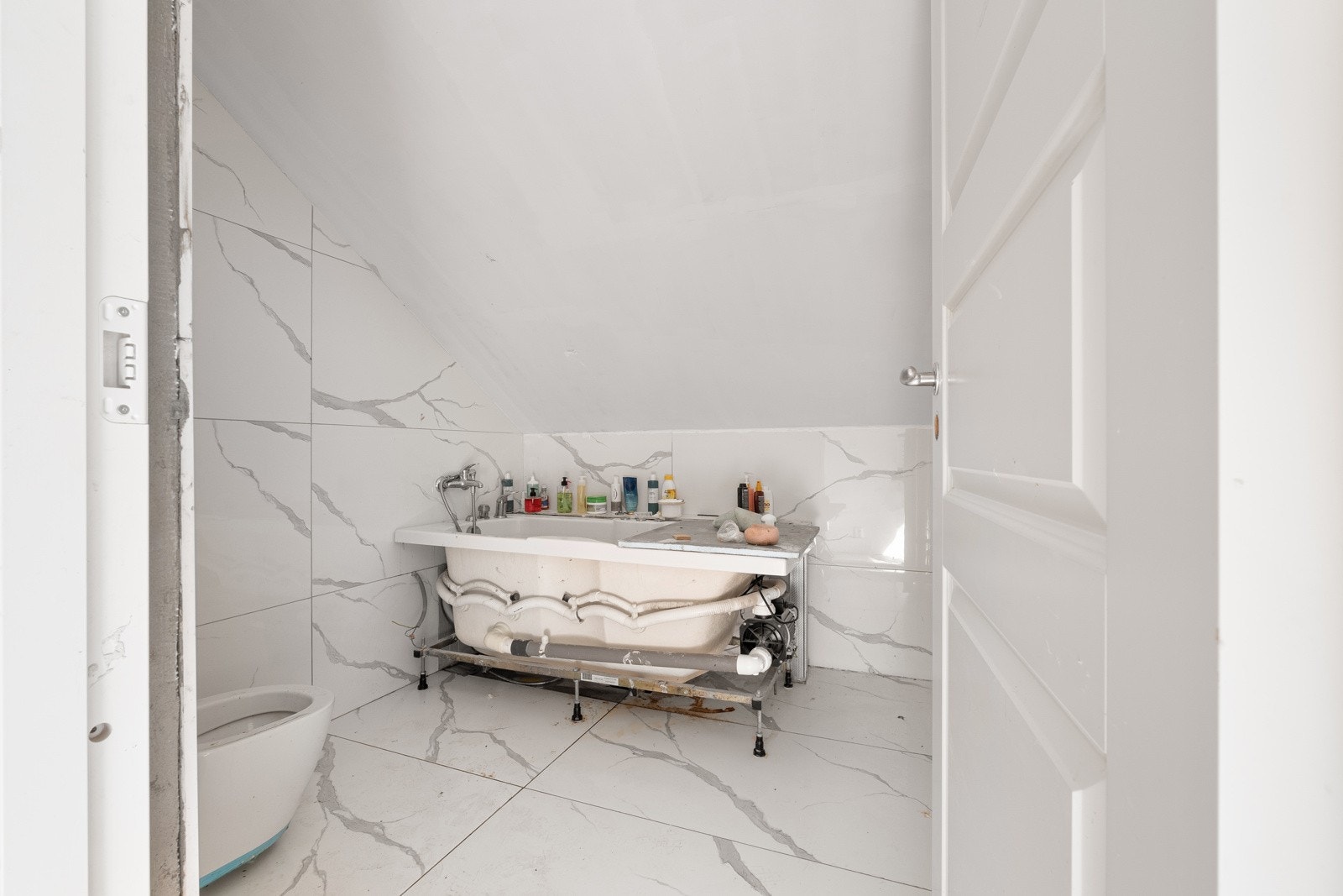 Baderom i 2. etasje har store lyse fliser på vegg og gulv, samt manglende fliser på wc-sisterme. Inventar med toalett og badekar. Badet er gitt tilstandsgrad 3 - fremstår som ufagmessig utført og uten dokumentasjon. Galleribilde