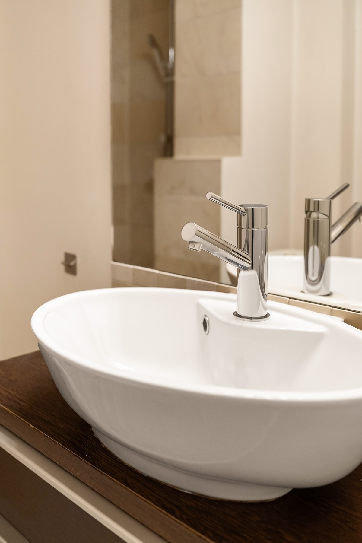 Moderne baderomsinnredning med skuffer for oppbevaring og ovenpåliggende porselensservant med blandebatteri. Galleribilde