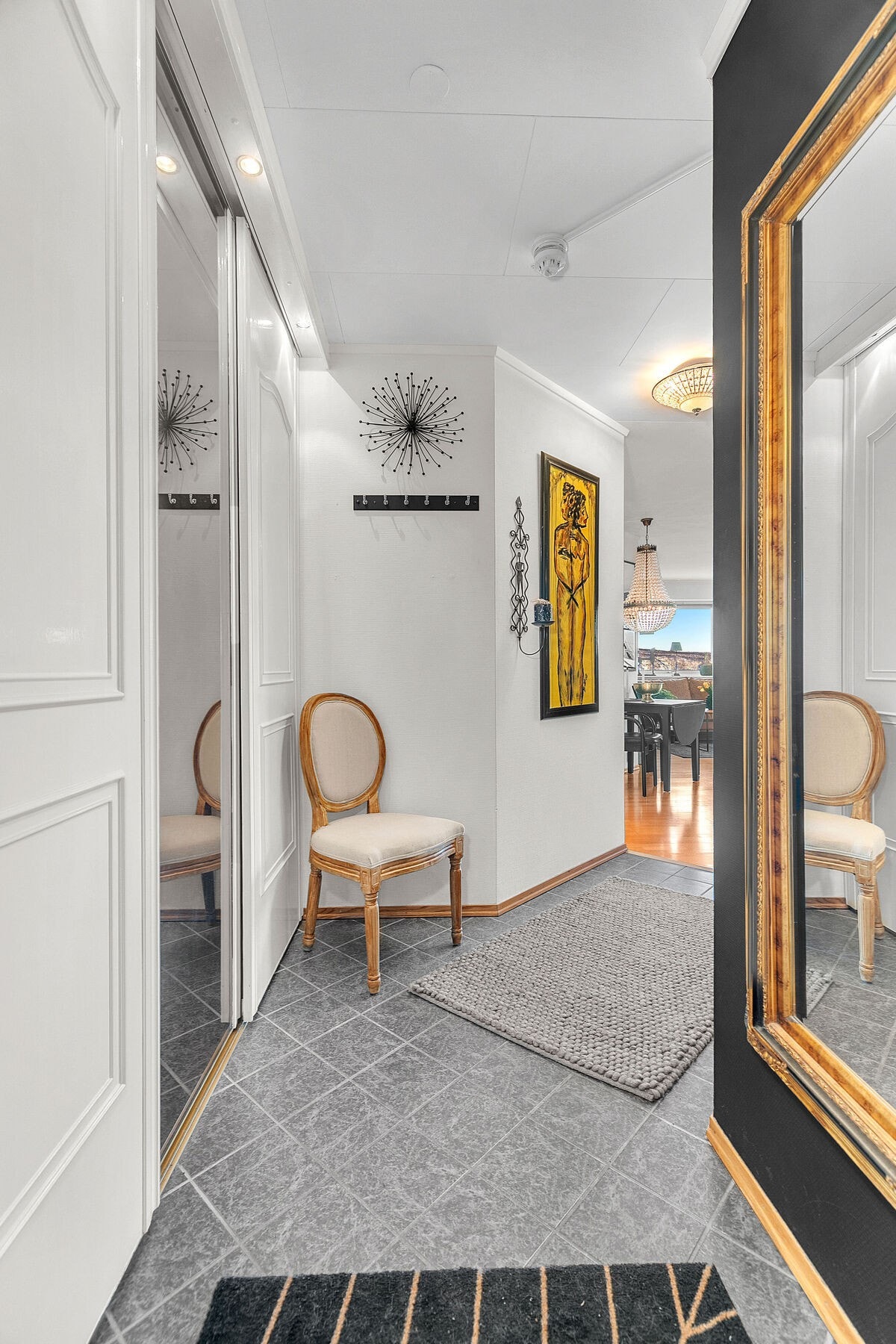 Pent inngangsparti med skyvedørsgarderobe, fliser på gulv og spotter. Galleribilde