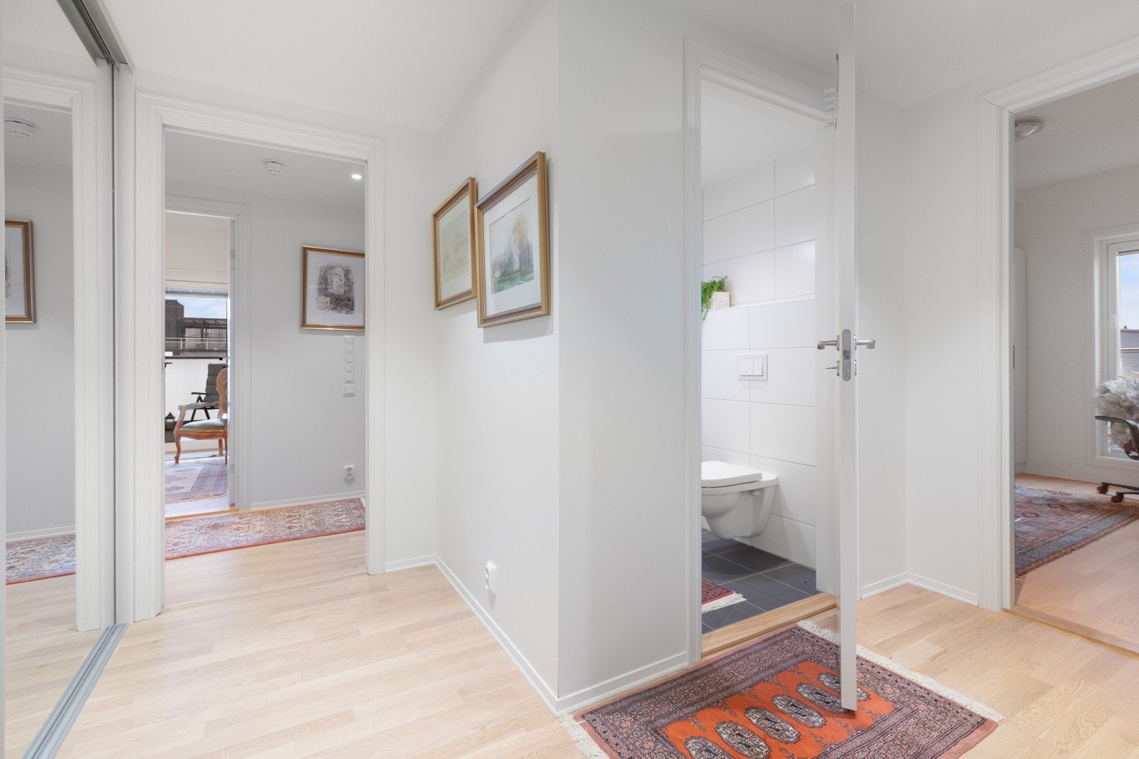 Velkommen inn! En ønskes velkommen inn i en lys og innbydende entré, hvor det er installert en praktisk skyvedørsgarderobe med speil Galleribilde