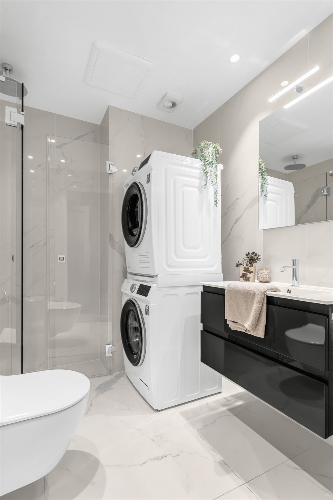 Vegghengt wc, dusjhjørne med glassdører, tile-insert linjesluk og innebygget takdusj og hånddusj fra Tapwell. Baderomsinnredning med store skuffer og armatur fra Tapwell samt vegghengt speil. Opplegg for vaskemaskin og tørketrommel. Galleribilde