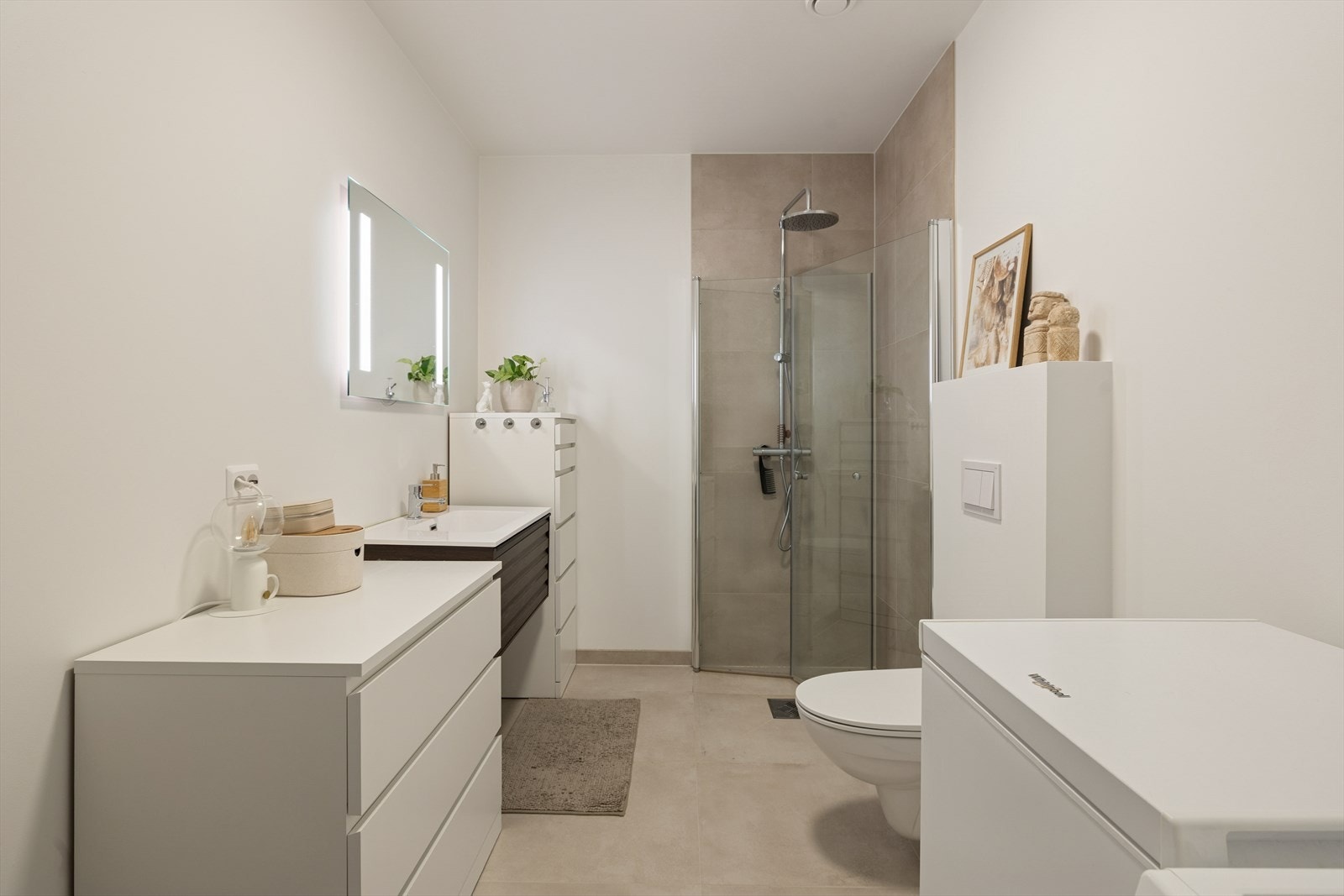 Baderom med servant nedfelt i innredning, dusjhjørne og vegghengt toalett. Galleribilde