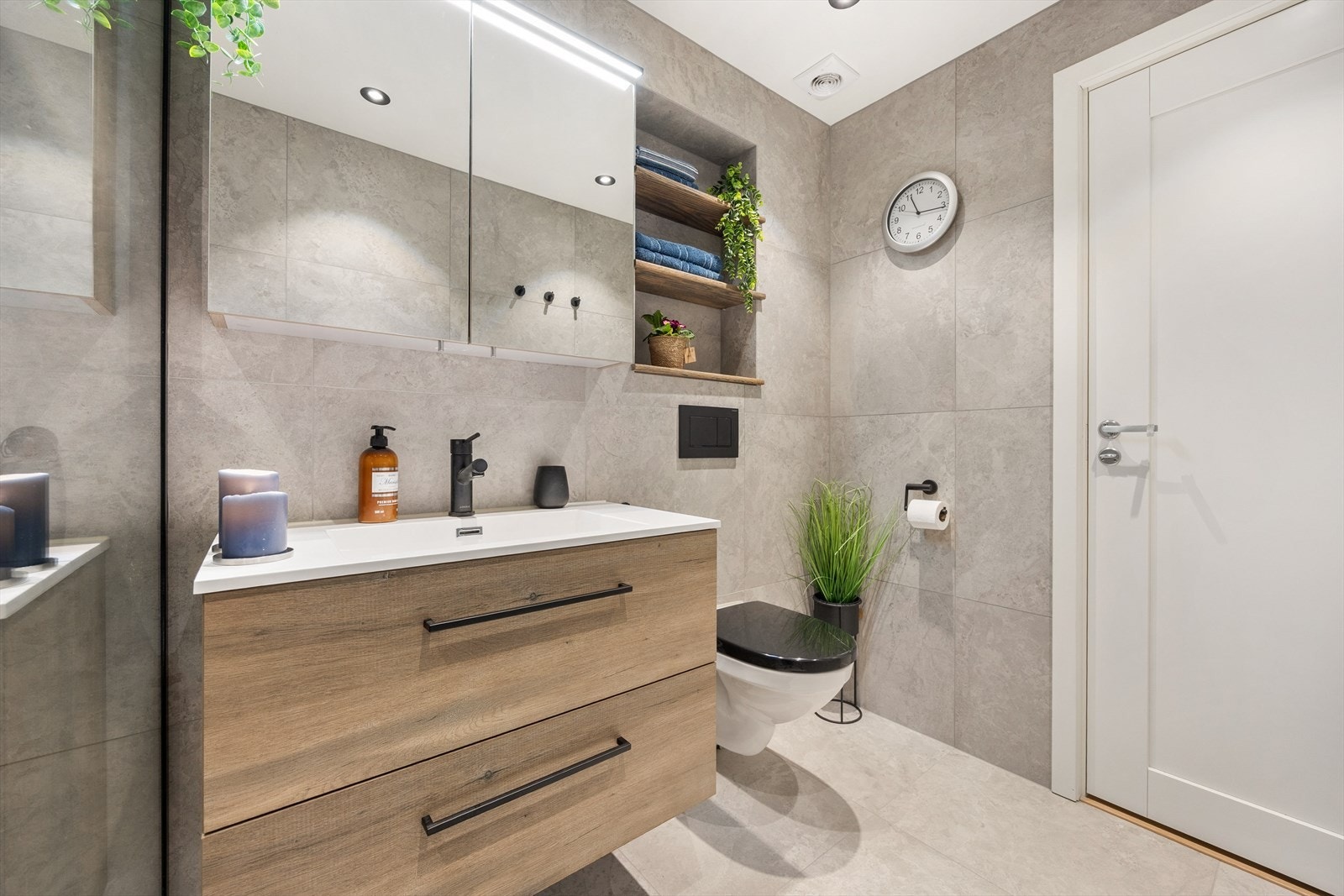 Badet er utstyrt med veggmontert toalett, downlights og servant med skuffeseksjon Galleribilde