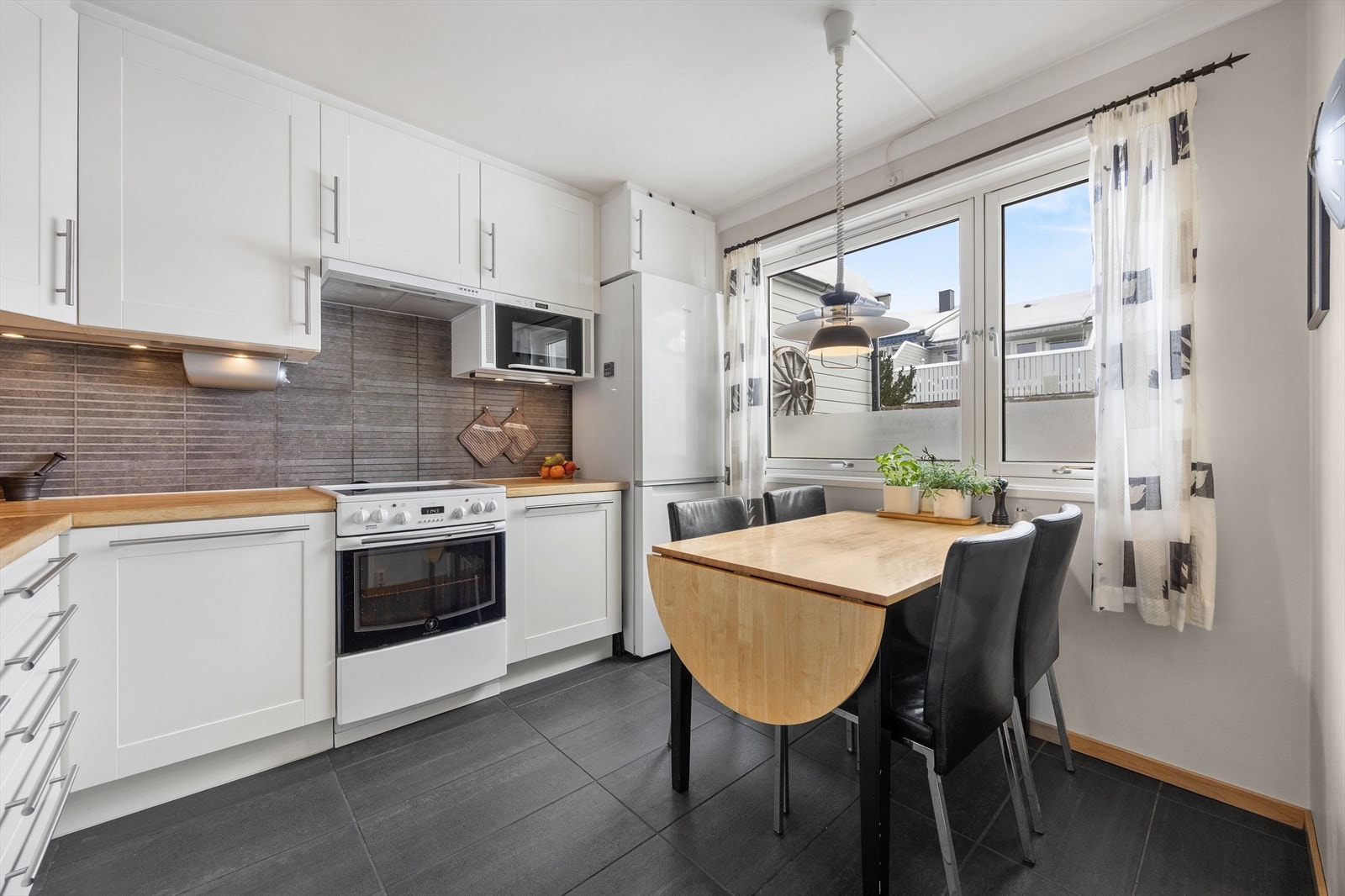 Kjøkkenet har en hyggelig spiseplass ved vinduet, perfekt for hverdagsmåltidene Galleribilde