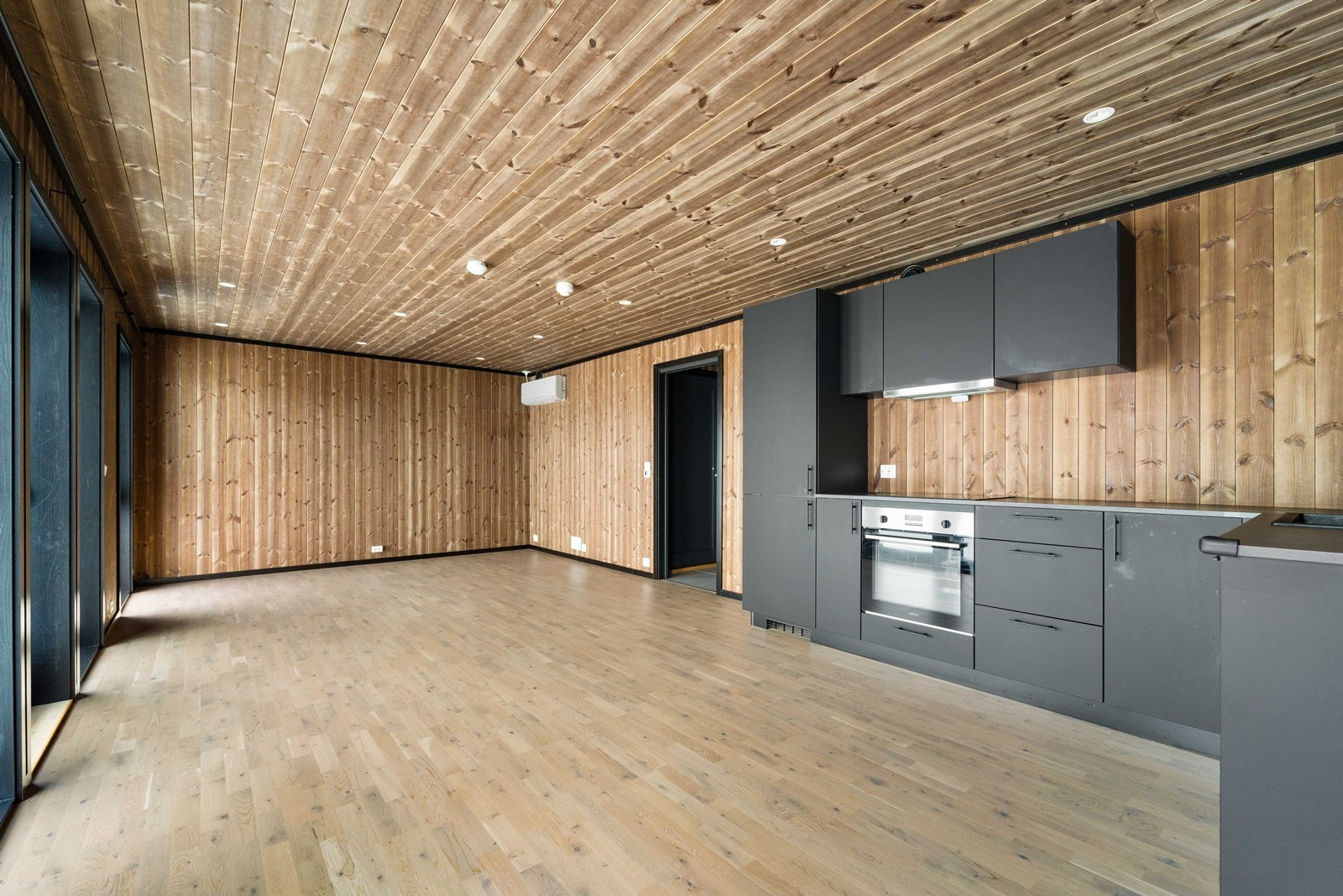 Romslig stue med kjøkken. Varmepumpe på veggen og terrasse rett utenfor. Galleribilde