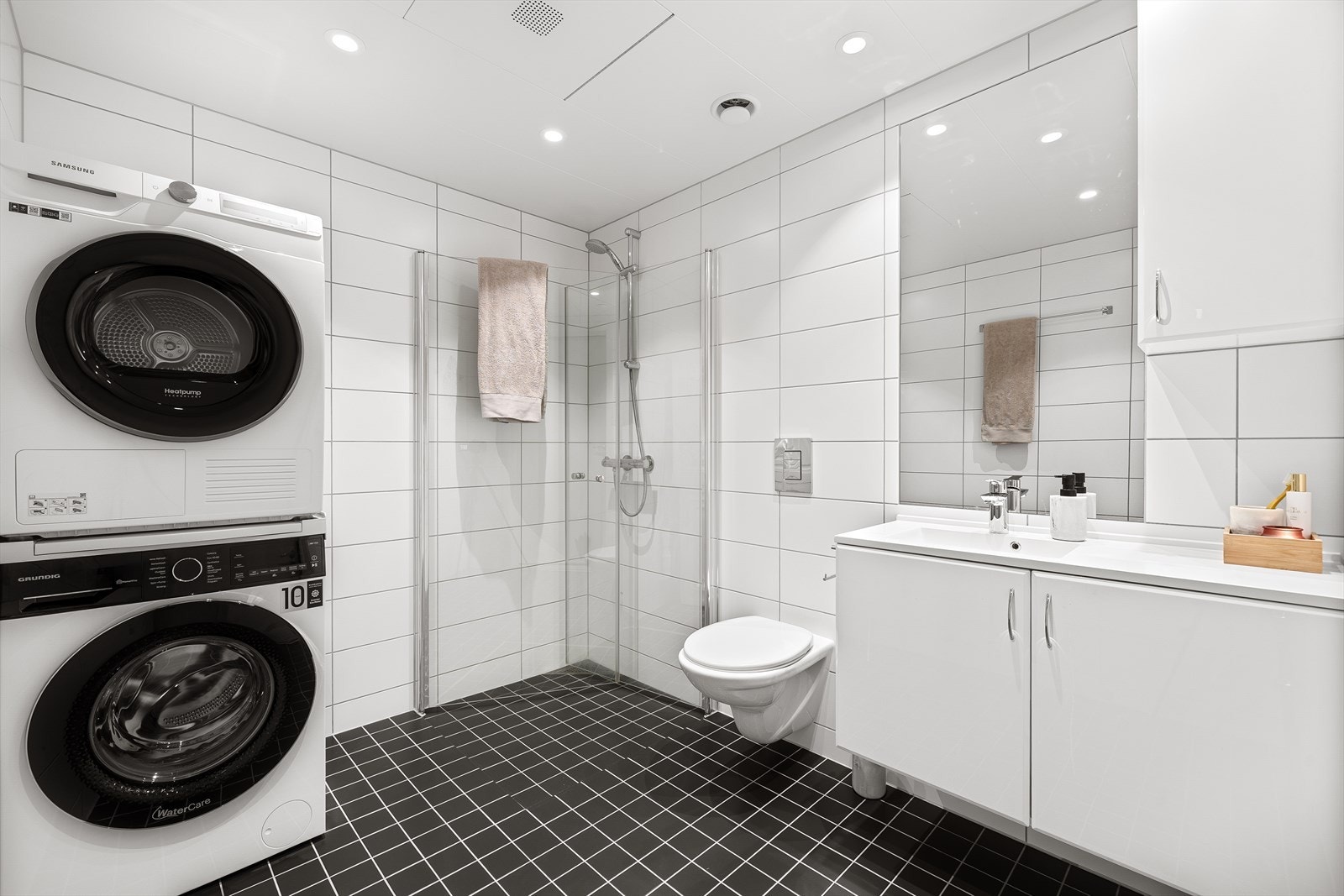 Lekkert og romslig bad med hvit, stilren innredning. Badet er utstyrt med servantskap, innfellbare dusjdører, veggmontert wc, rørfordelingsskap og mekanisk avtrekk. Galleribilde