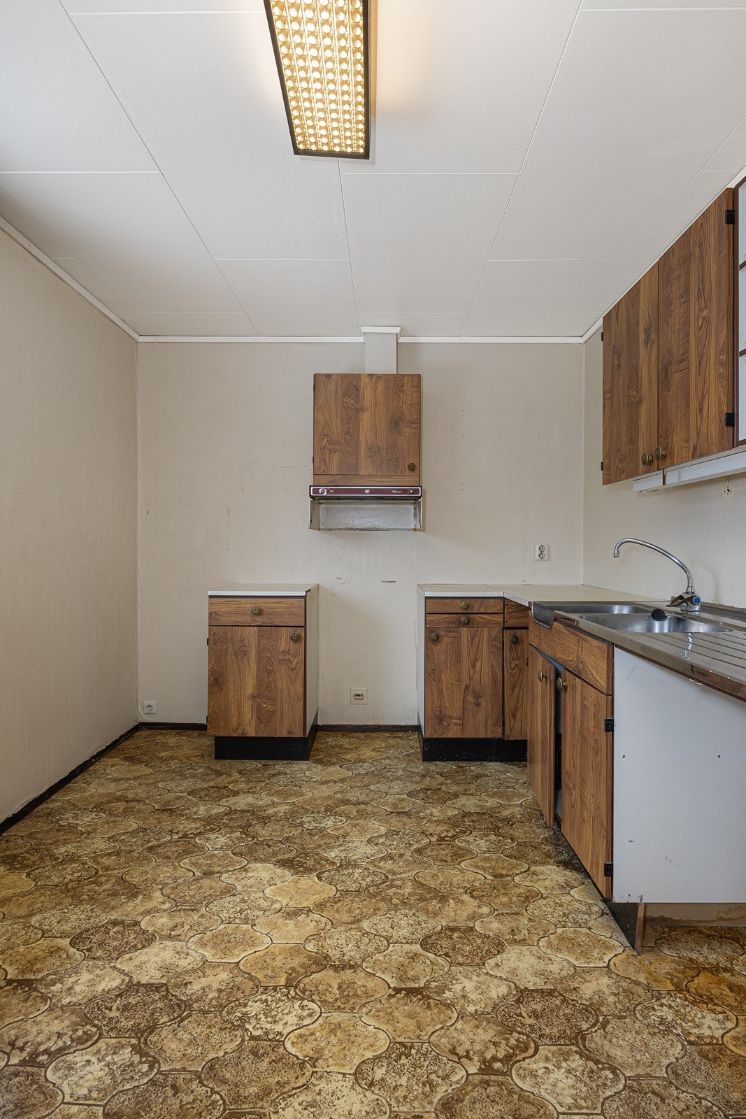 Innredningen har glatte, mørke fronter og hvit laminatbenkeplate med benkebeslag i stål med oppvaskkum og utslagsvask. Galleribilde