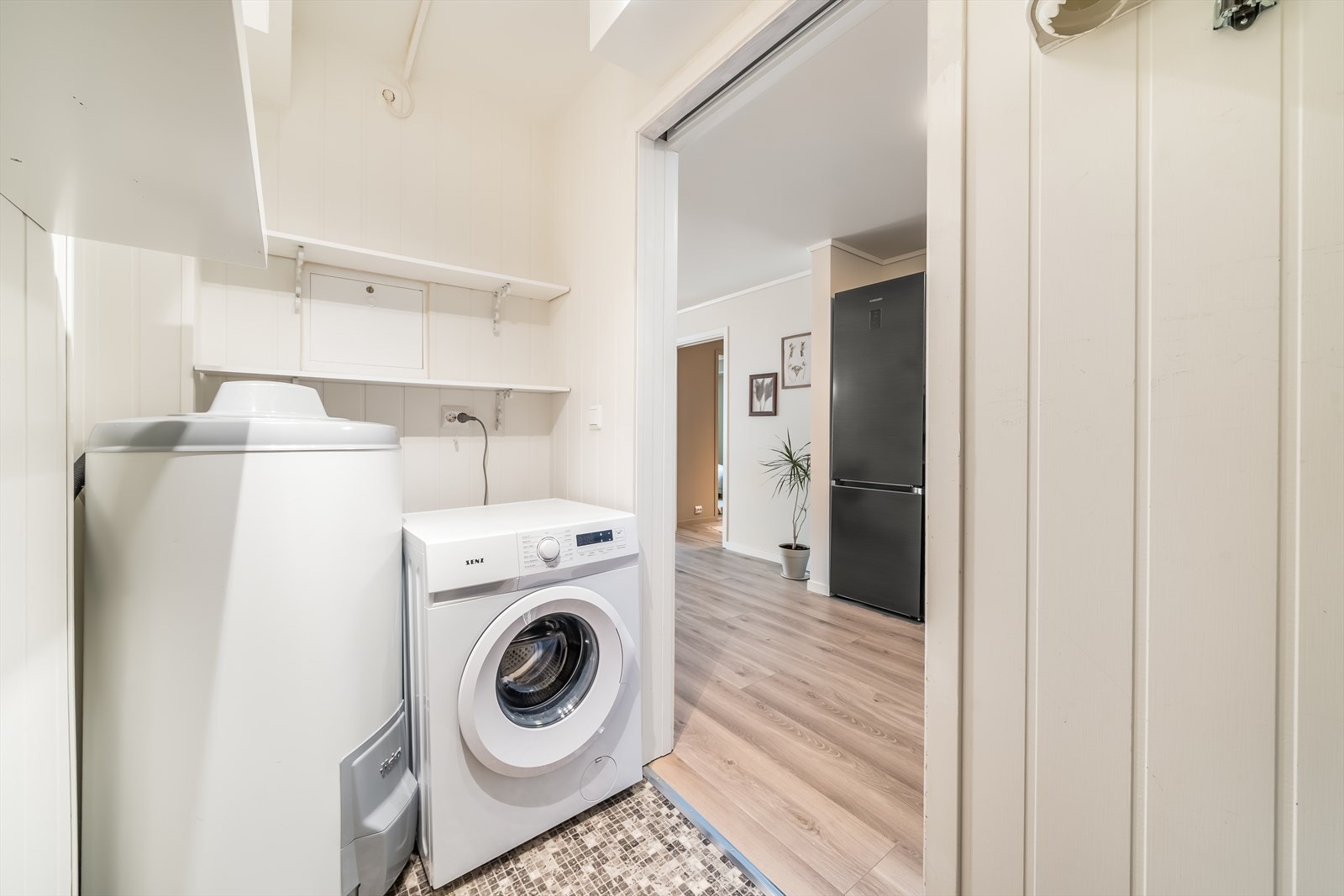 Praktisk vaskerom med oppbevaringsmuligheter og plass til både vaskemaskin og varmtvannsbereder. Galleribilde