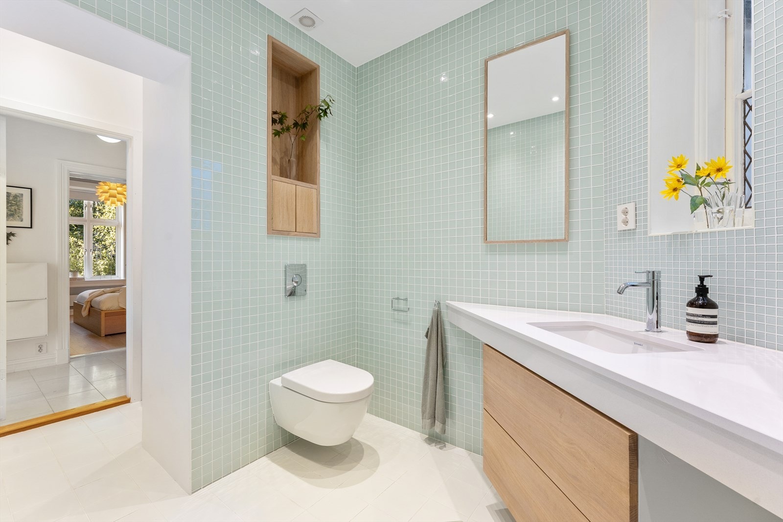 Funksjonelt baderom med spesialtilpasset høyskap og veggskap, vegghengt toalett og elektrisk avtrekk. Galleribilde