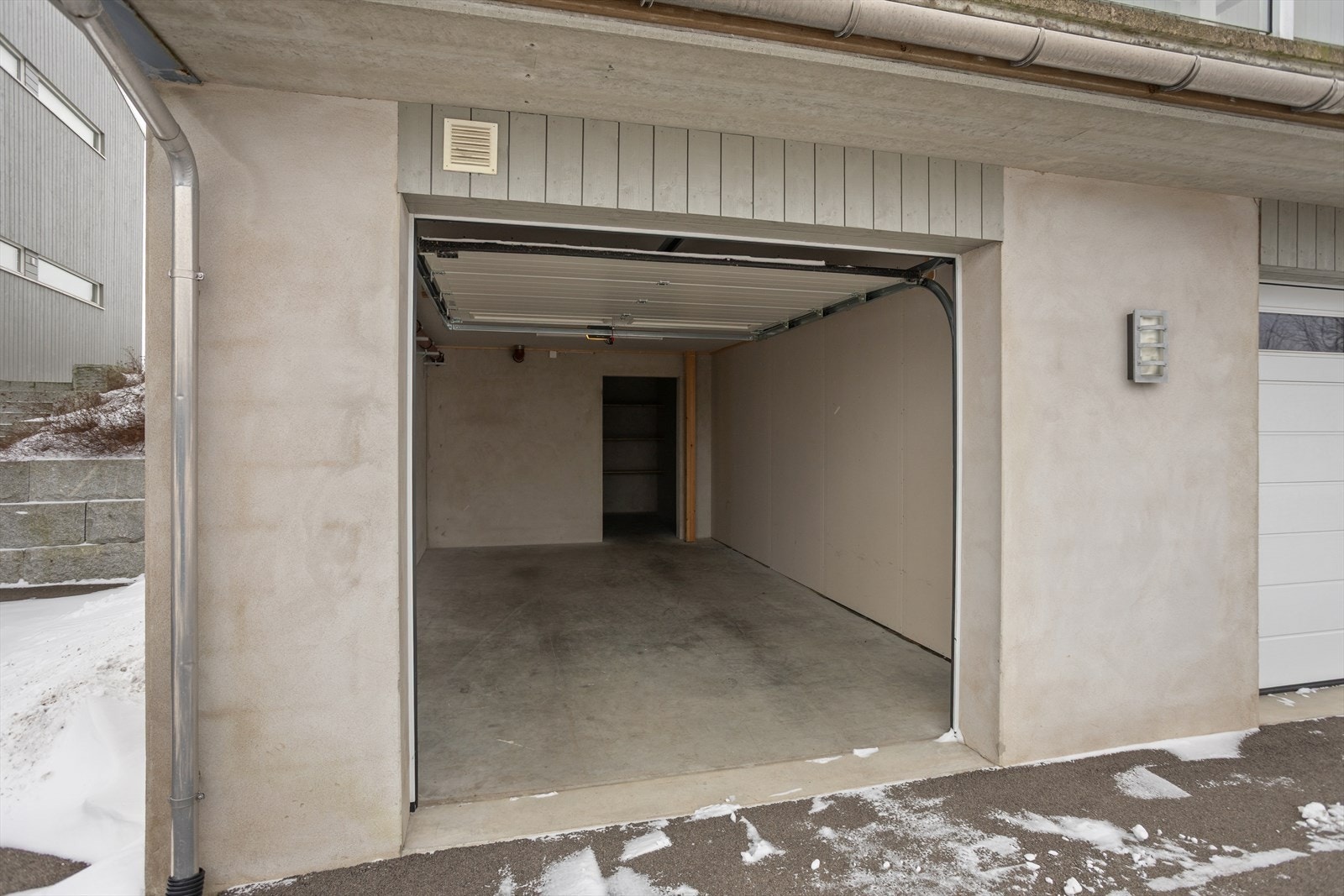 Garasjen er integrert i bygningen, og leilighets plass er gunstig plassert, nærmest byggets hovedinngangsparti. Gulvdekke av betong og innvendige vegger som er platekledd og av pusset mur. Det er for øvrig innlagt både lys og stikk-/strømkontakt. Galleribilde