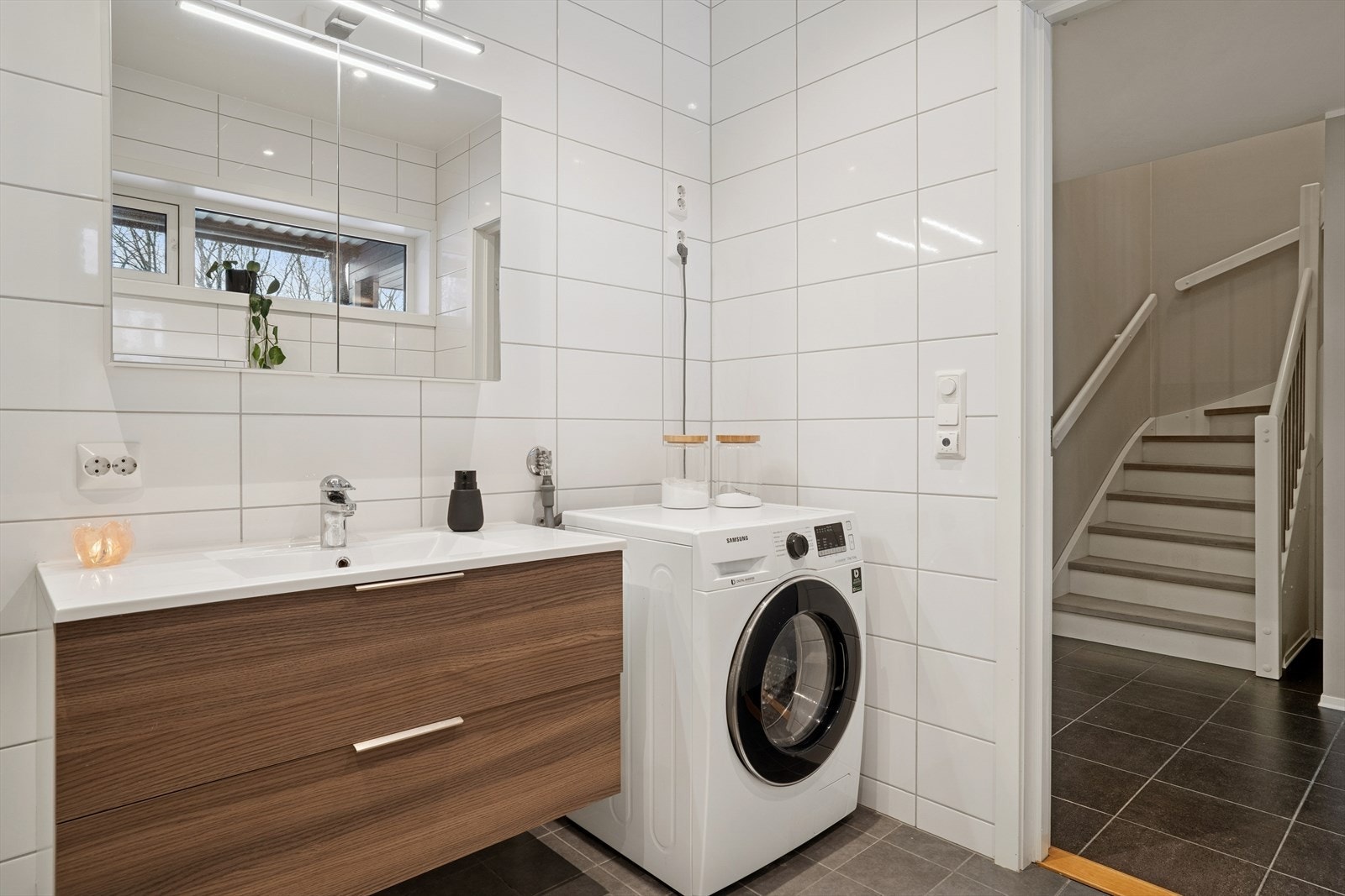 Badet er utført med mørke gulvfliser og hvite veggfliser Galleribilde