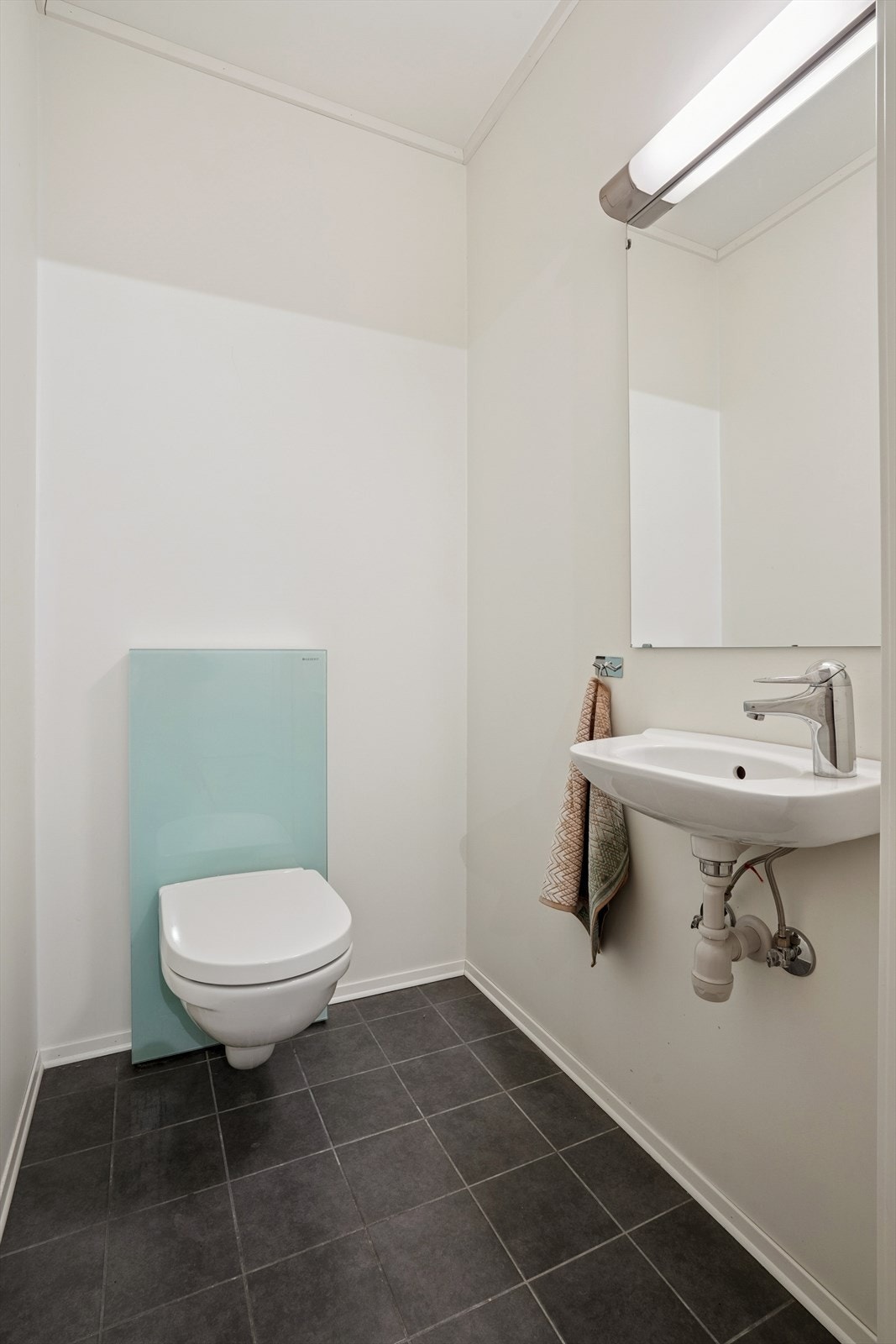 Det er også eget toalettrom med flislagt gulv - Her er det vegghengt toalett og servant på vegg med speil over Galleribilde