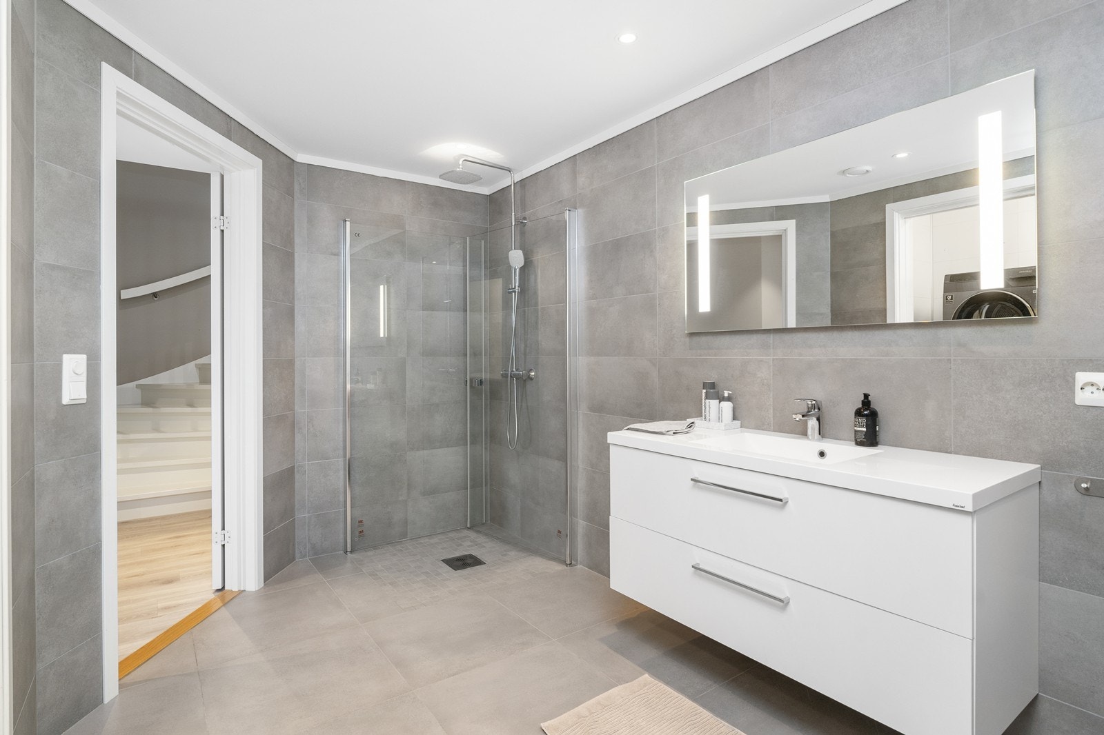 Romslig bad/vaskerom med flislagte gulv og vegger. Downligths i tak. Galleribilde