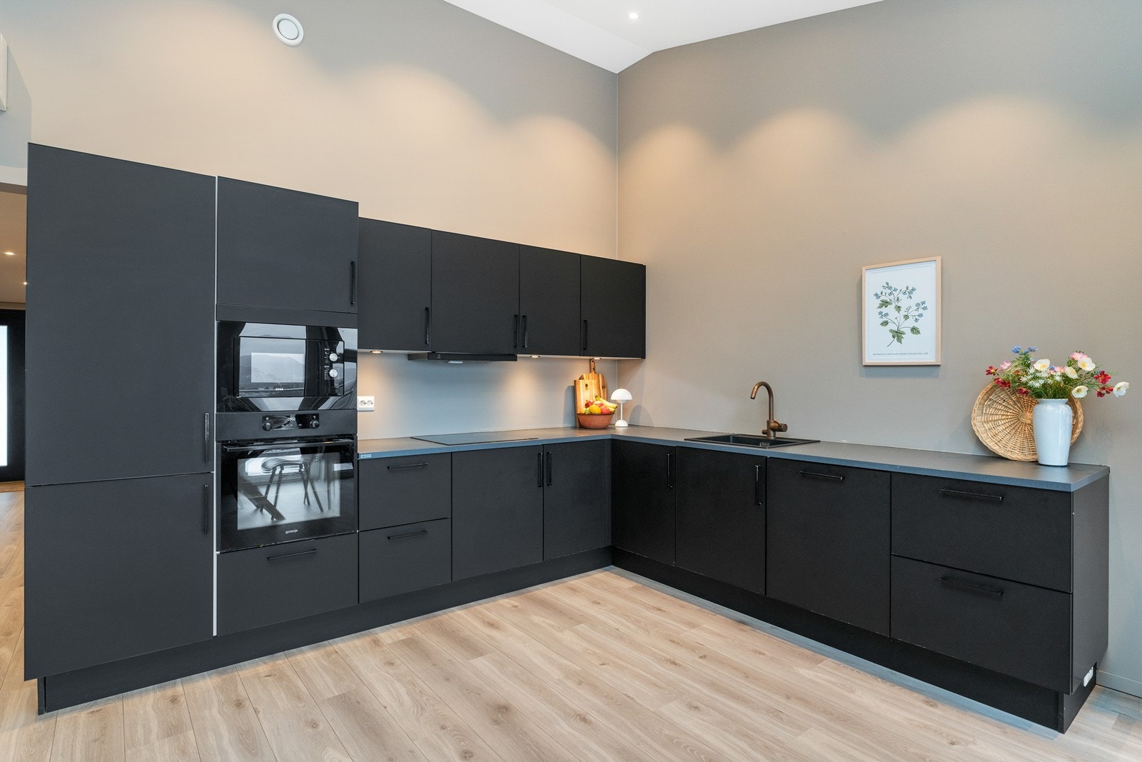 Stilig sort kjøkkeninnredning med integrerte hvitevarer. God skap -og benkeplass. Galleribilde