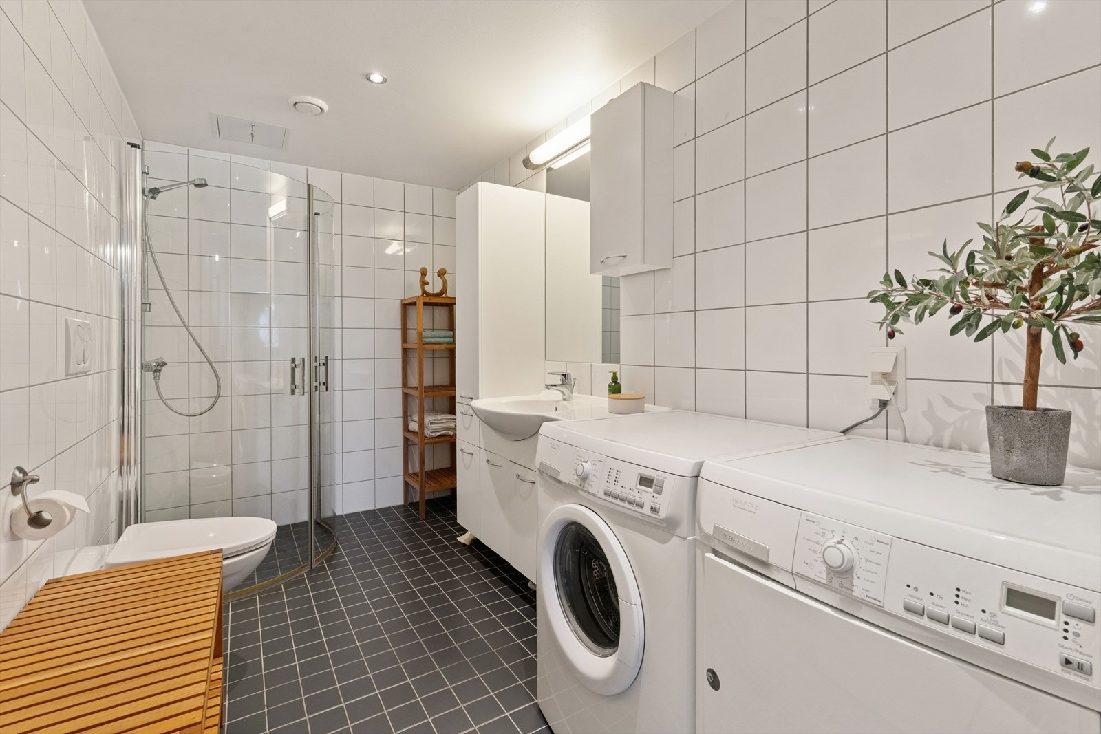 Pent, flislagt baderom med tidløst design, som kombineres som vaskerom. Galleribilde