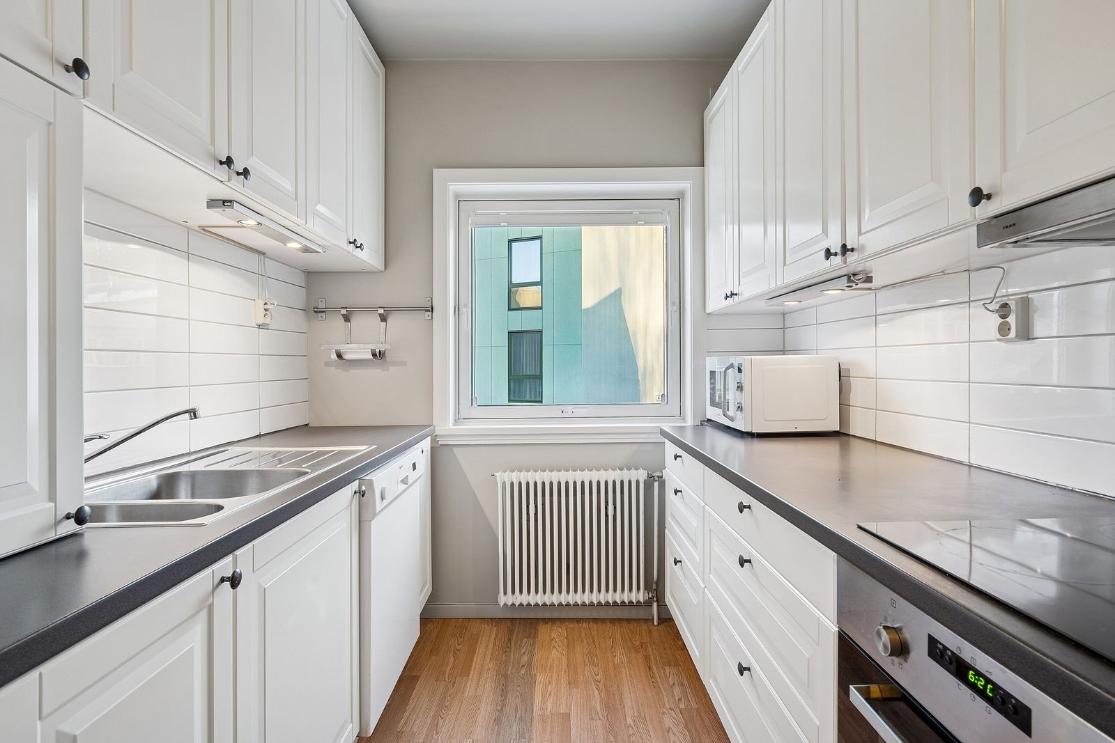 Pent og nymalt kjøkken med hvitevarer som oppvaskmaskin, komfyr, platetopp, mikro og kombiskap. Galleribilde