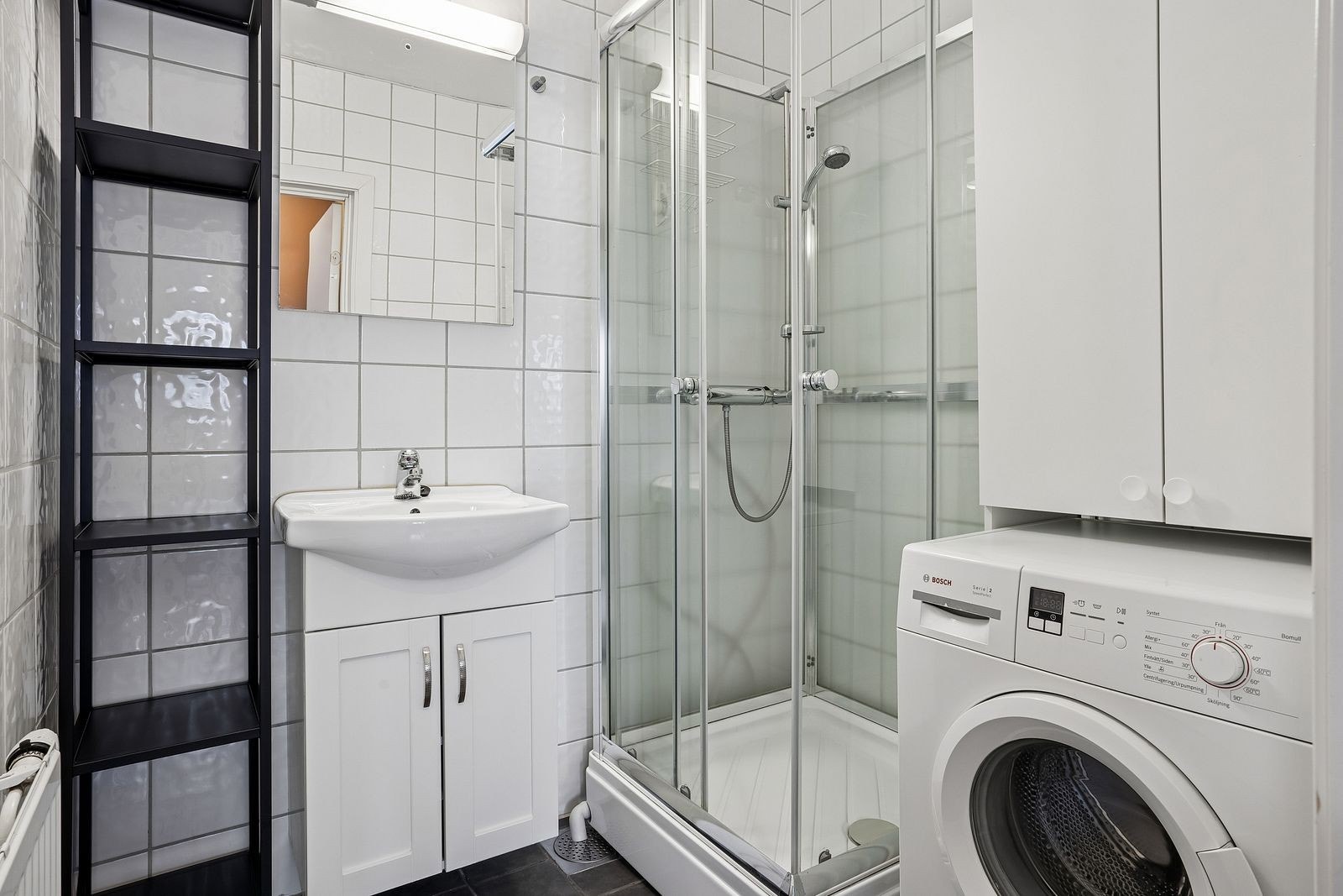 Flislagt bad med dusjkabinett og vaskemaskin. Toalettrom er adskilt fra badet. Galleribilde